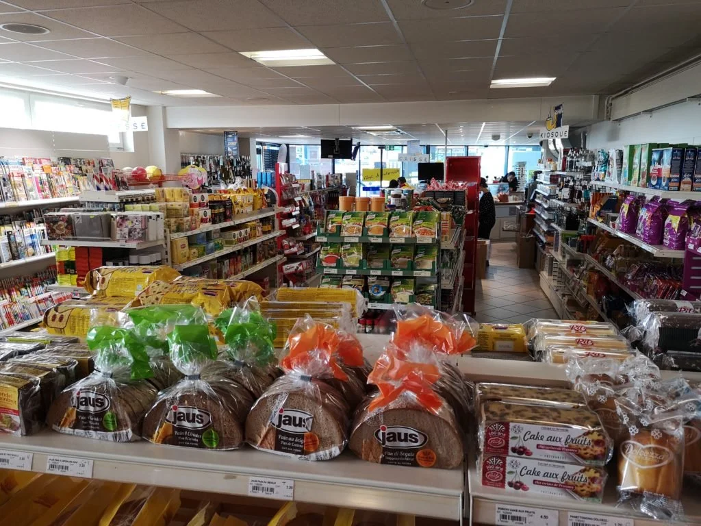 Rayons d'épicerie avec produits alimentaires, pâtisseries, et jouets dans une supérette.