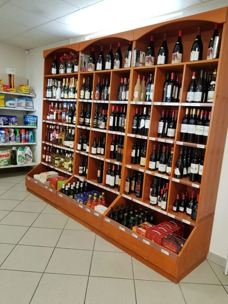 Rayonnage en bois rempli de bouteilles de vin dans une cave ou un supermarché.