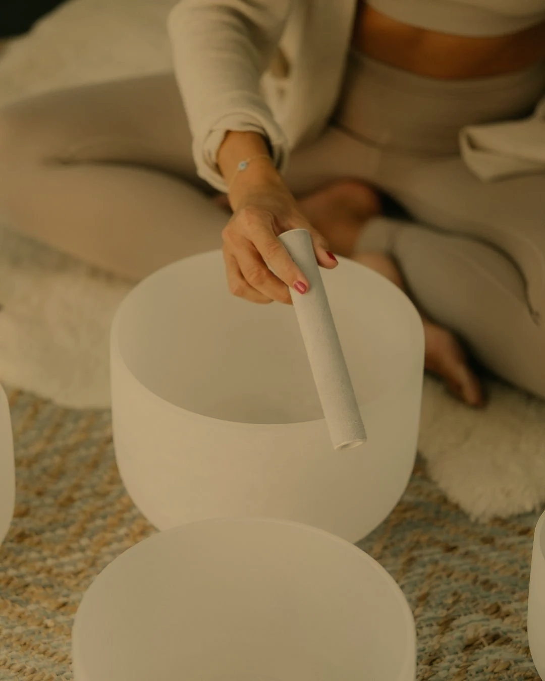 En person spelar på en vit klockspel i ett mysigt hem, sittande på en mjuk matta.