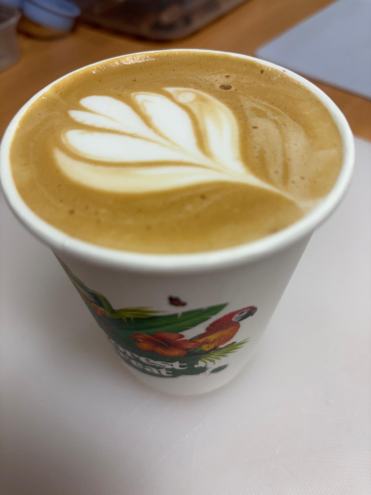 A cup of coffee with latte art on top, floating on a white surface.