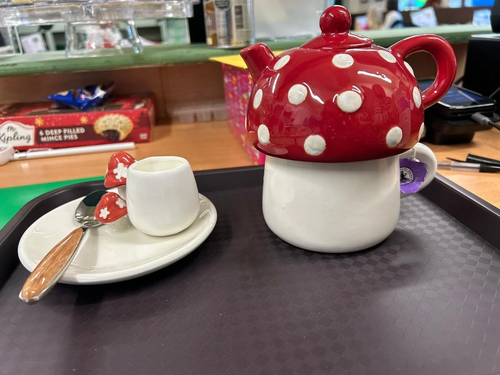 Ceramic teapot with a red and white polka dot design, small matching creamer and mushroom-shaped sugar on a tray.