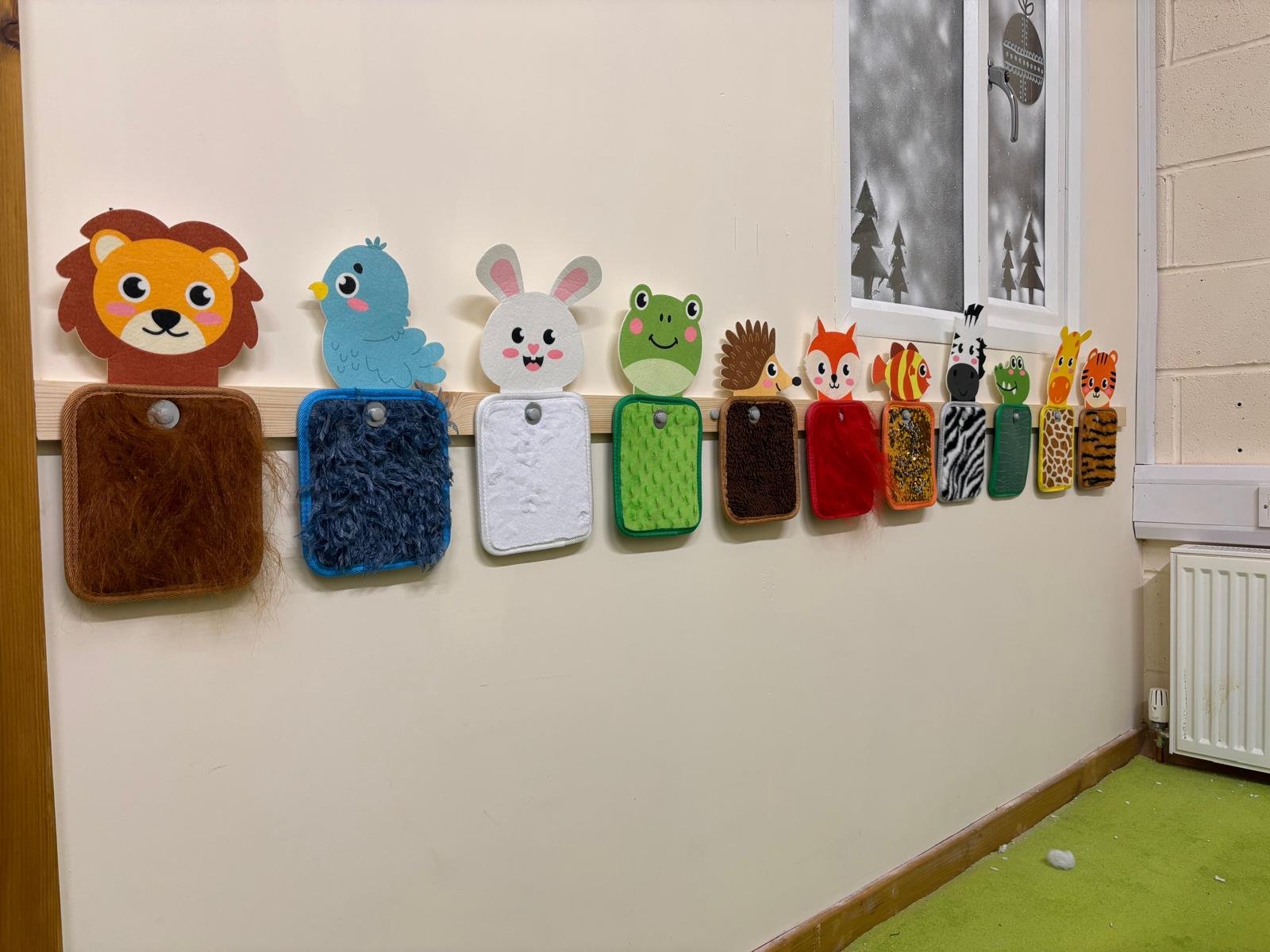 Animal-themed felt storyboards hung on a wall, featuring a lion, bird, rabbit, frog, hedgehog, fox, zebra, giraffe, and tiger, each with a rectangular base.