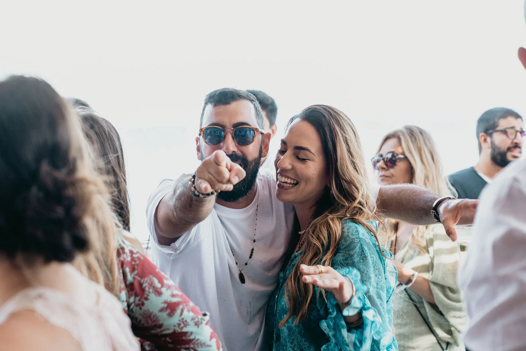 Group of people at a lively social gathering, smiling, chatting, and enjoying each other's company outdoors.