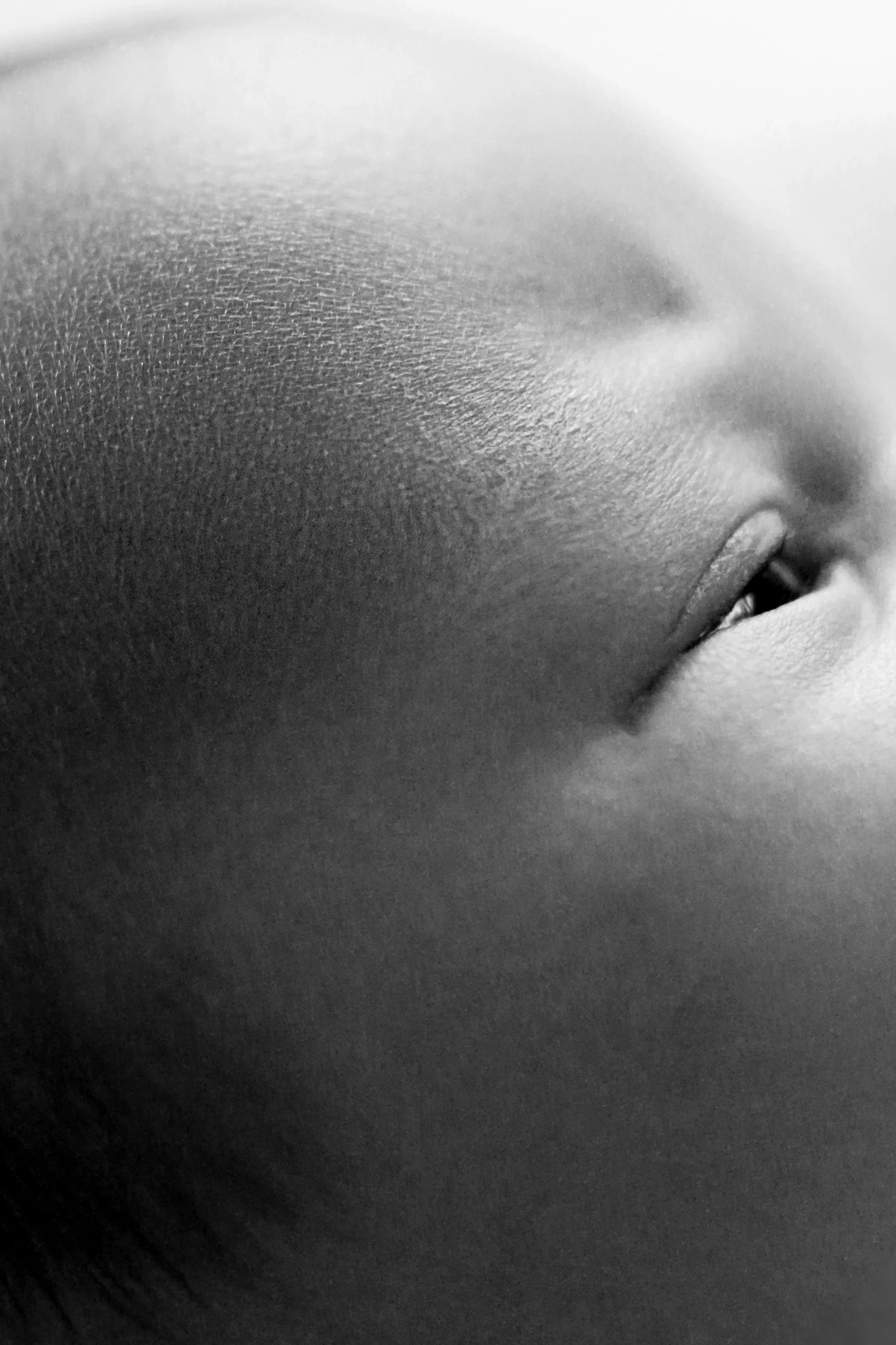 Close-up black and white photograph of a person's face showing their eyes with detailed skin texture.