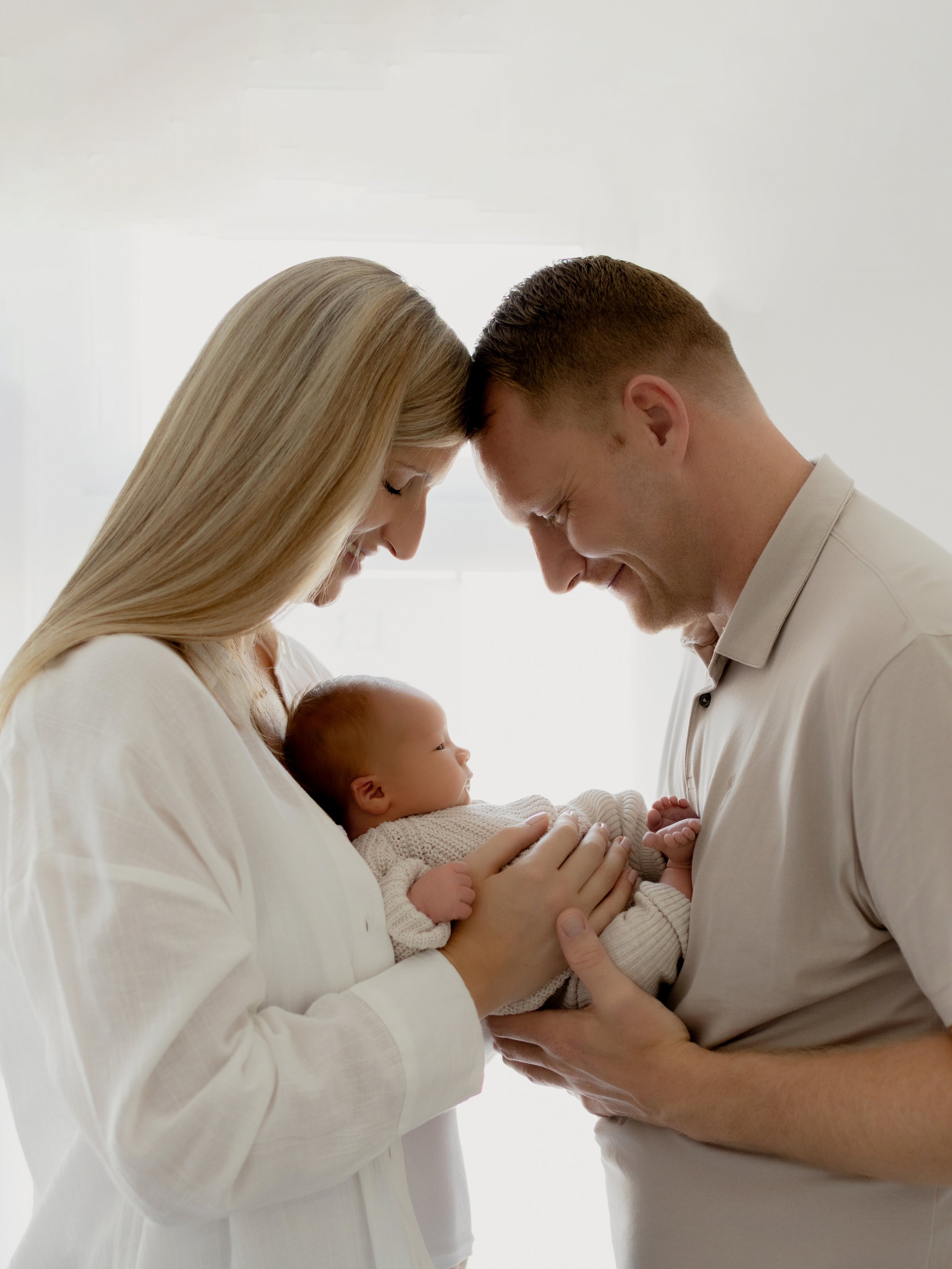 New parents holding their newborn baby during a relaxed studio photography session in South Ockendon, Essex