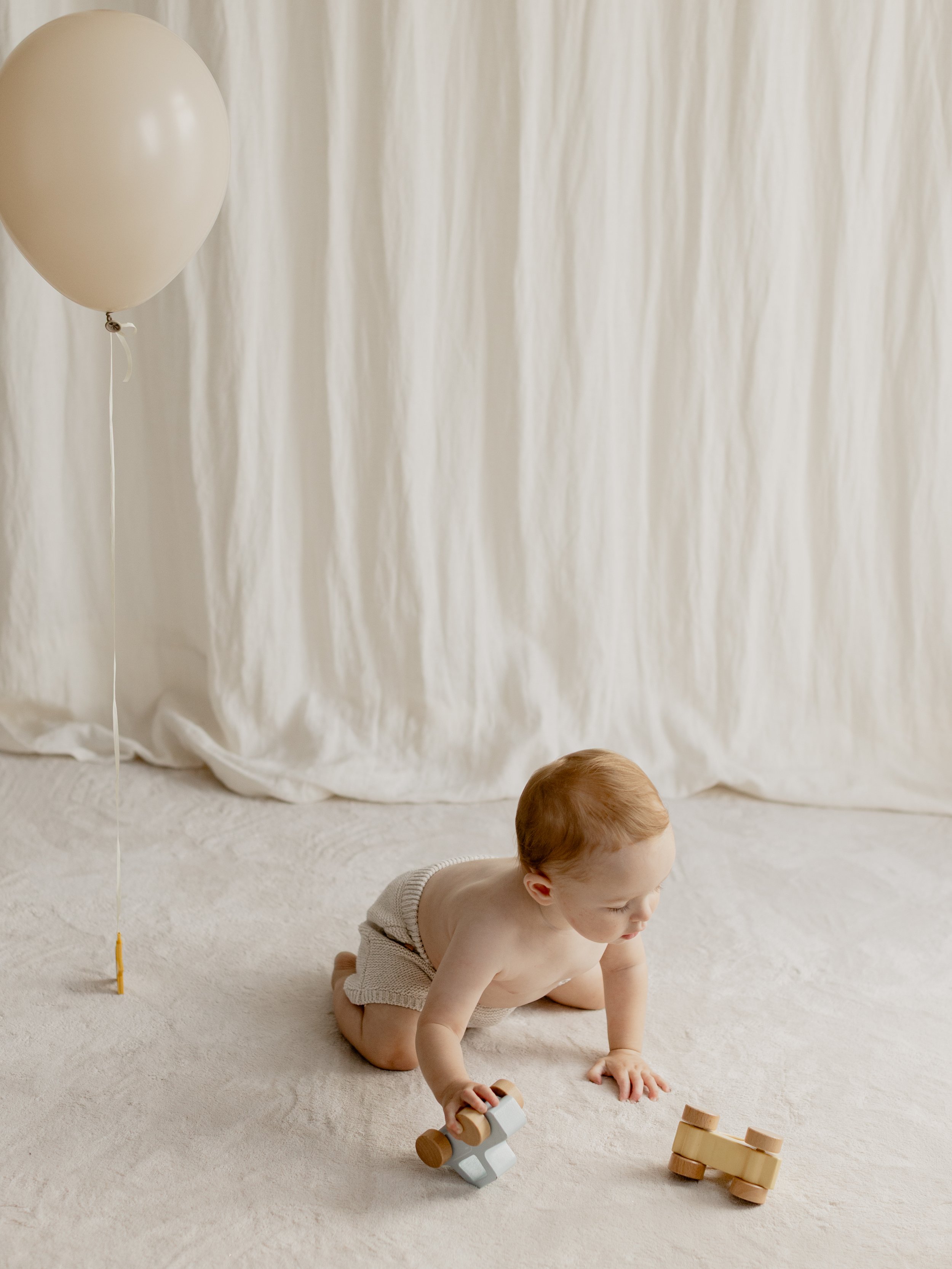 Baby playing with wooden toys during a milestone photography session in Essex.