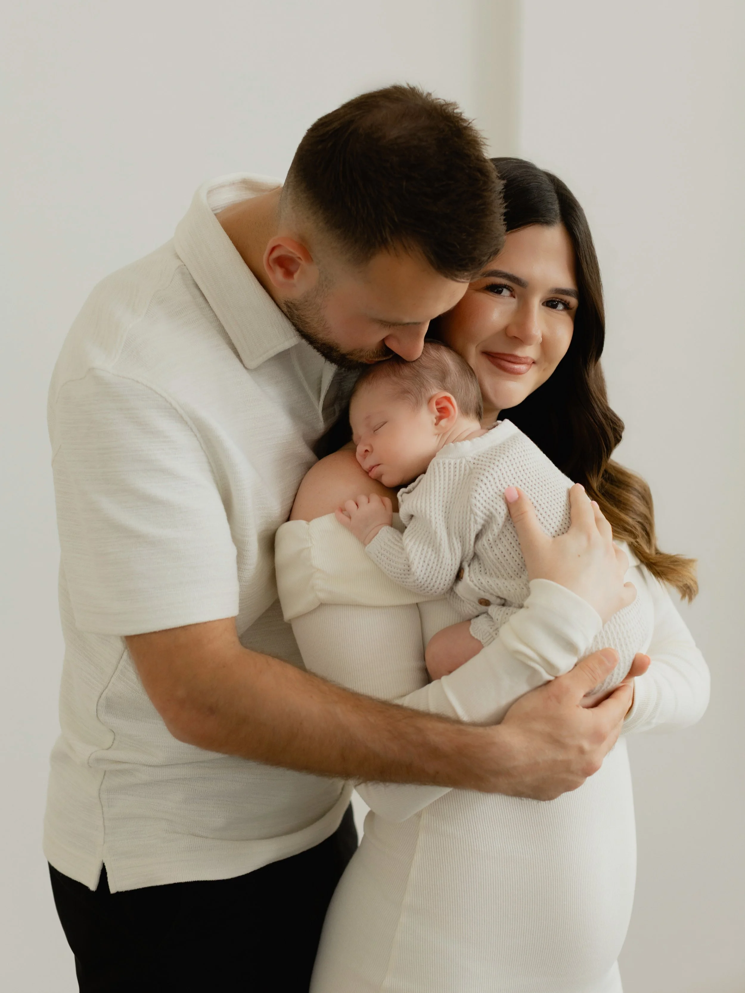 Parents cuddling their newborn baby during a natural newborn photography session in South Ockendon, Essex