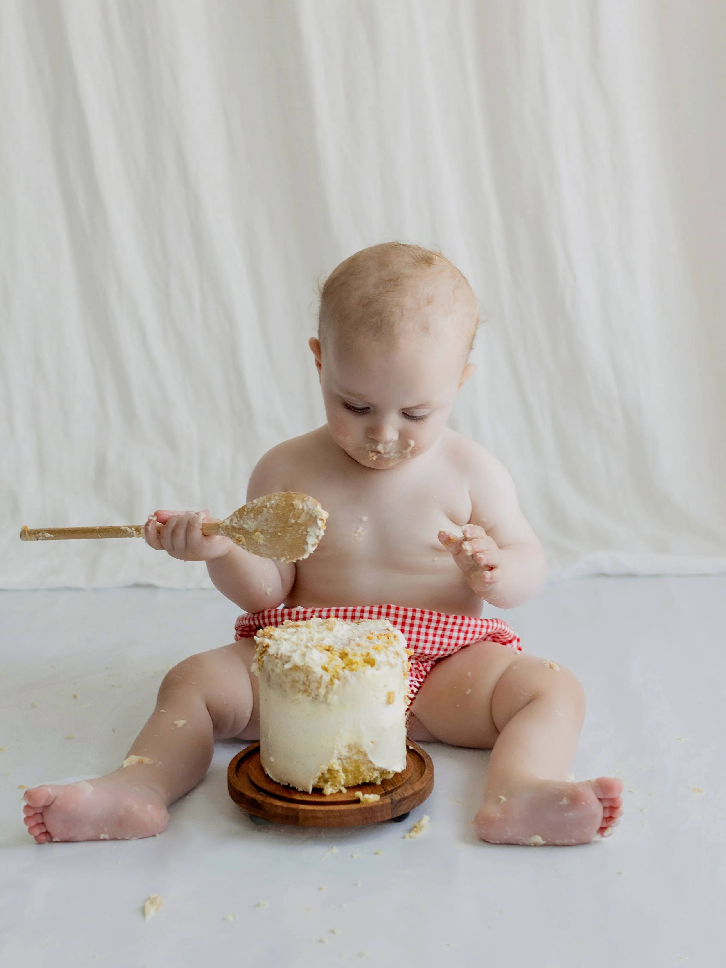 Baby enjoying a first birthday cake smash during a studio photography session in Essex