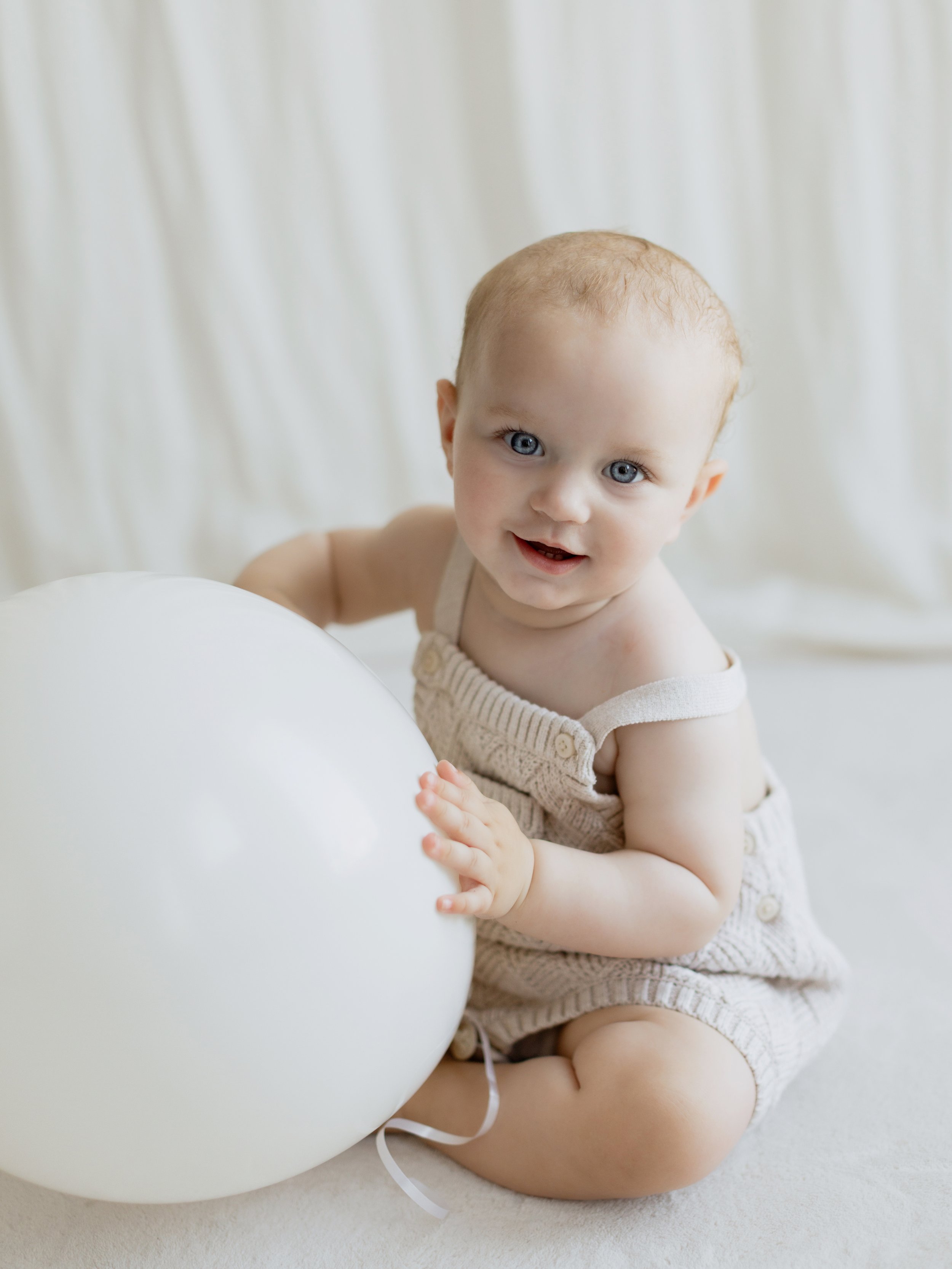 Baby portrait with a white balloon during a first birthday cake smash session in South Ockendon, Essex