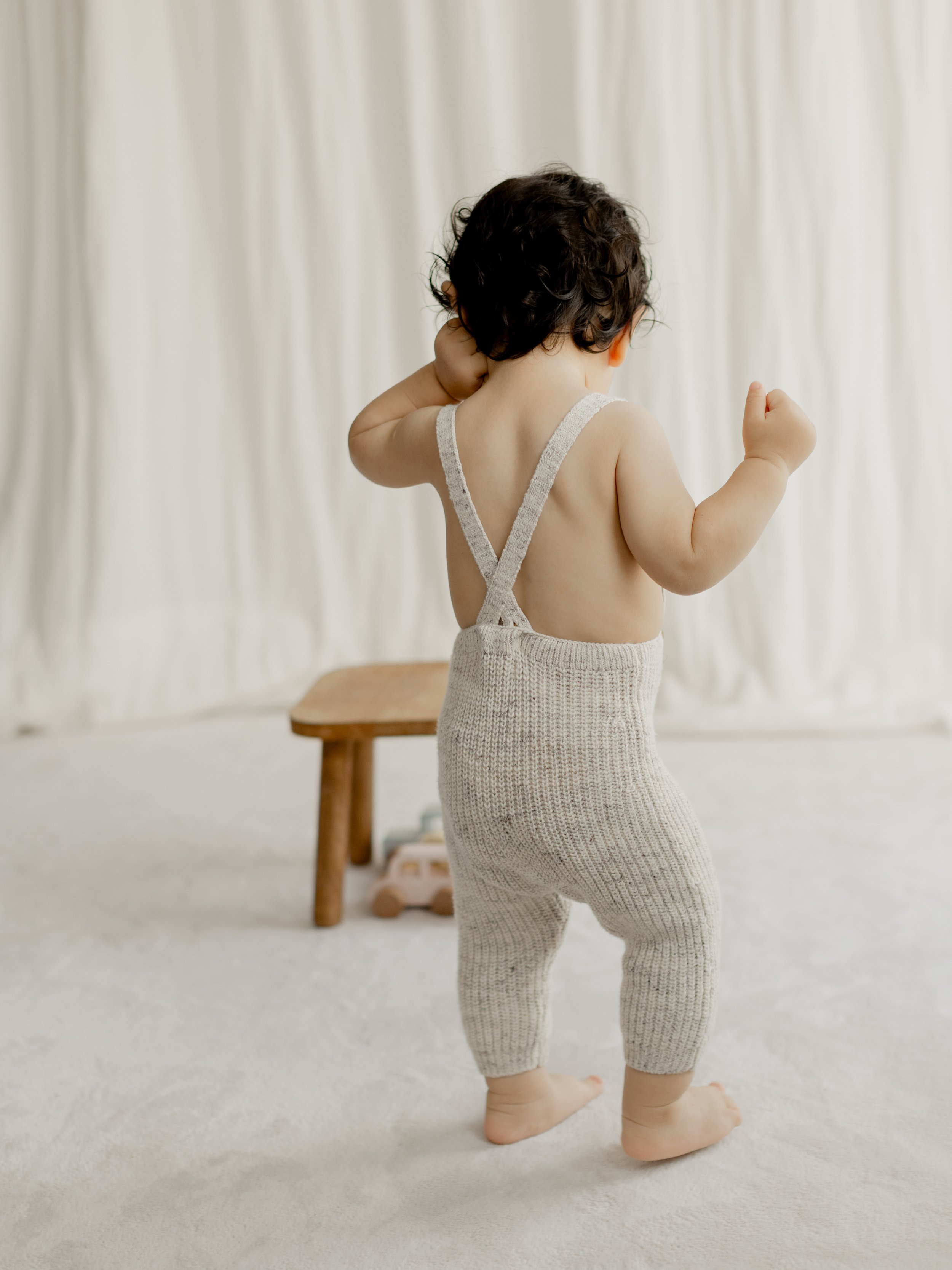 Baby standing and exploring during a natural milestone photography session in the studio.
