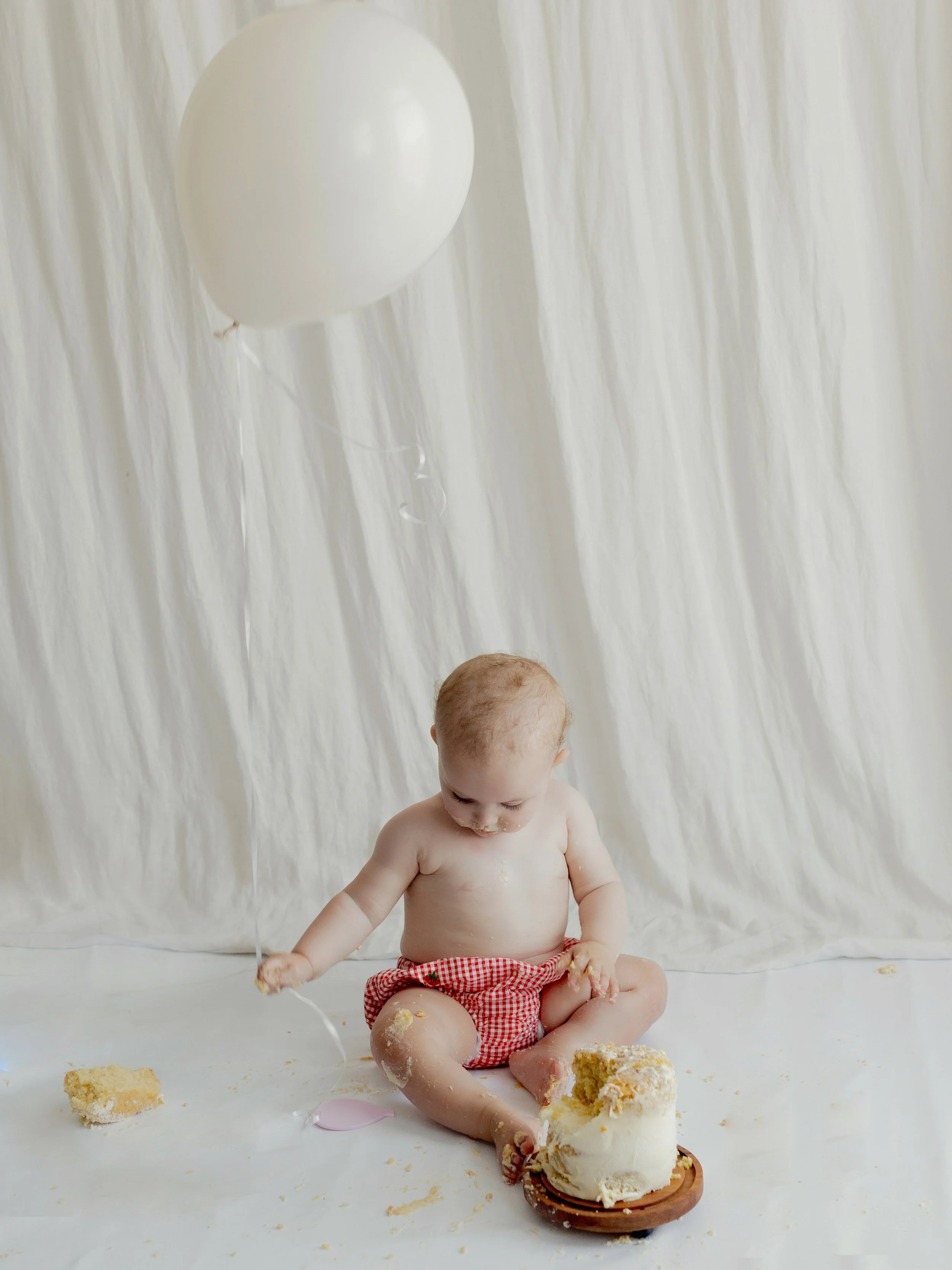 First birthday cake smash photography session with a simple balloon setup in South Ockendon, Essex