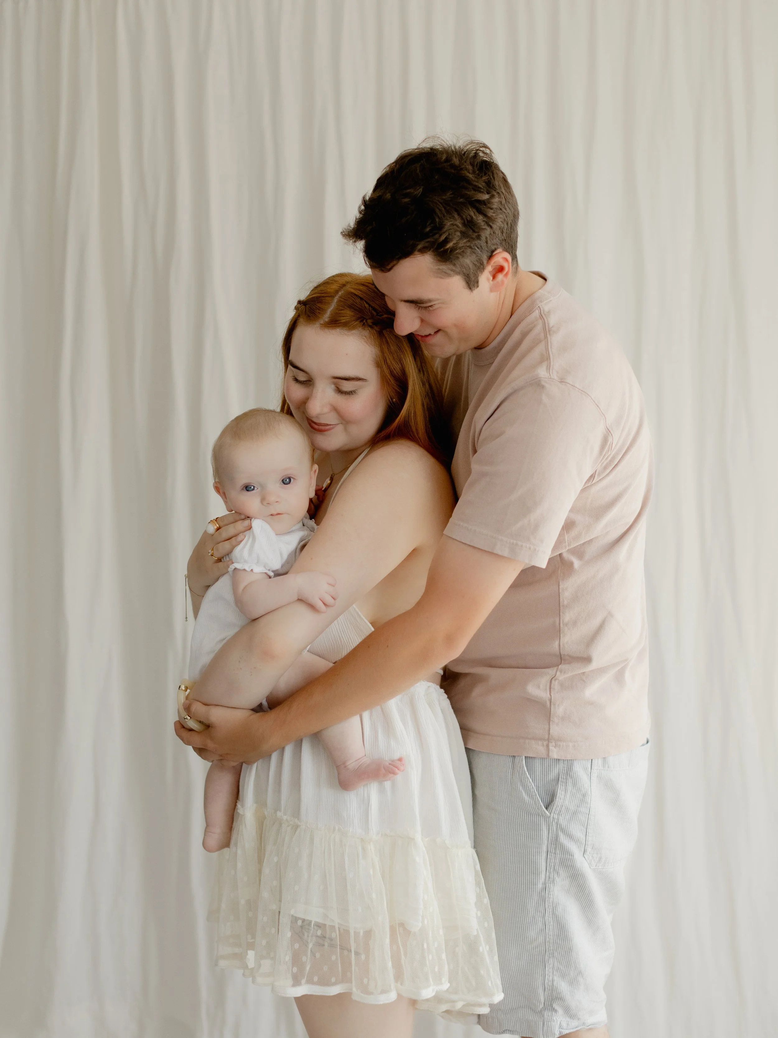 Parents cuddling their baby during a relaxed family portrait session at the South Ockendon studio.