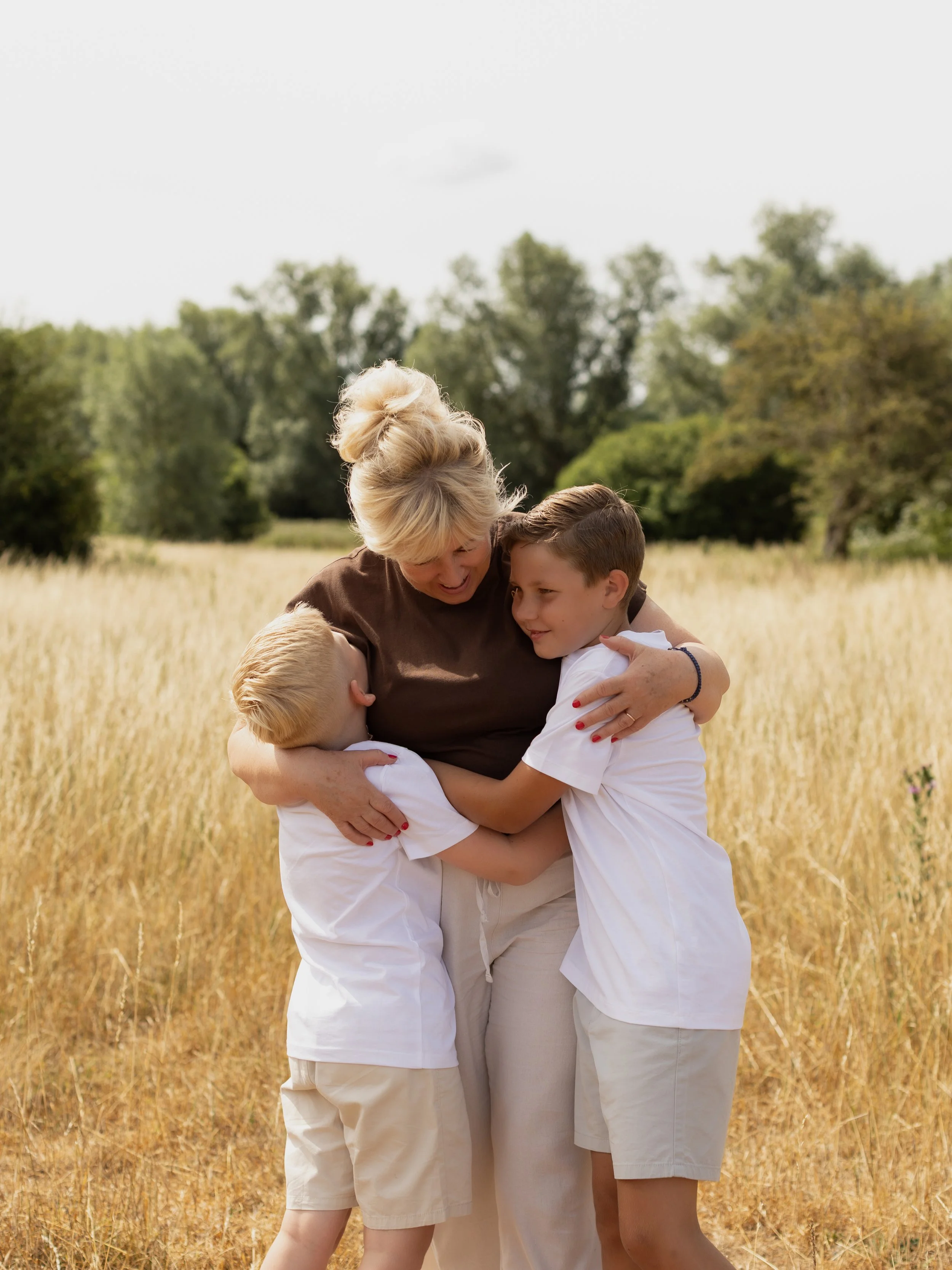 Grandmother cuddling two children during an outdoor extended family photography session.