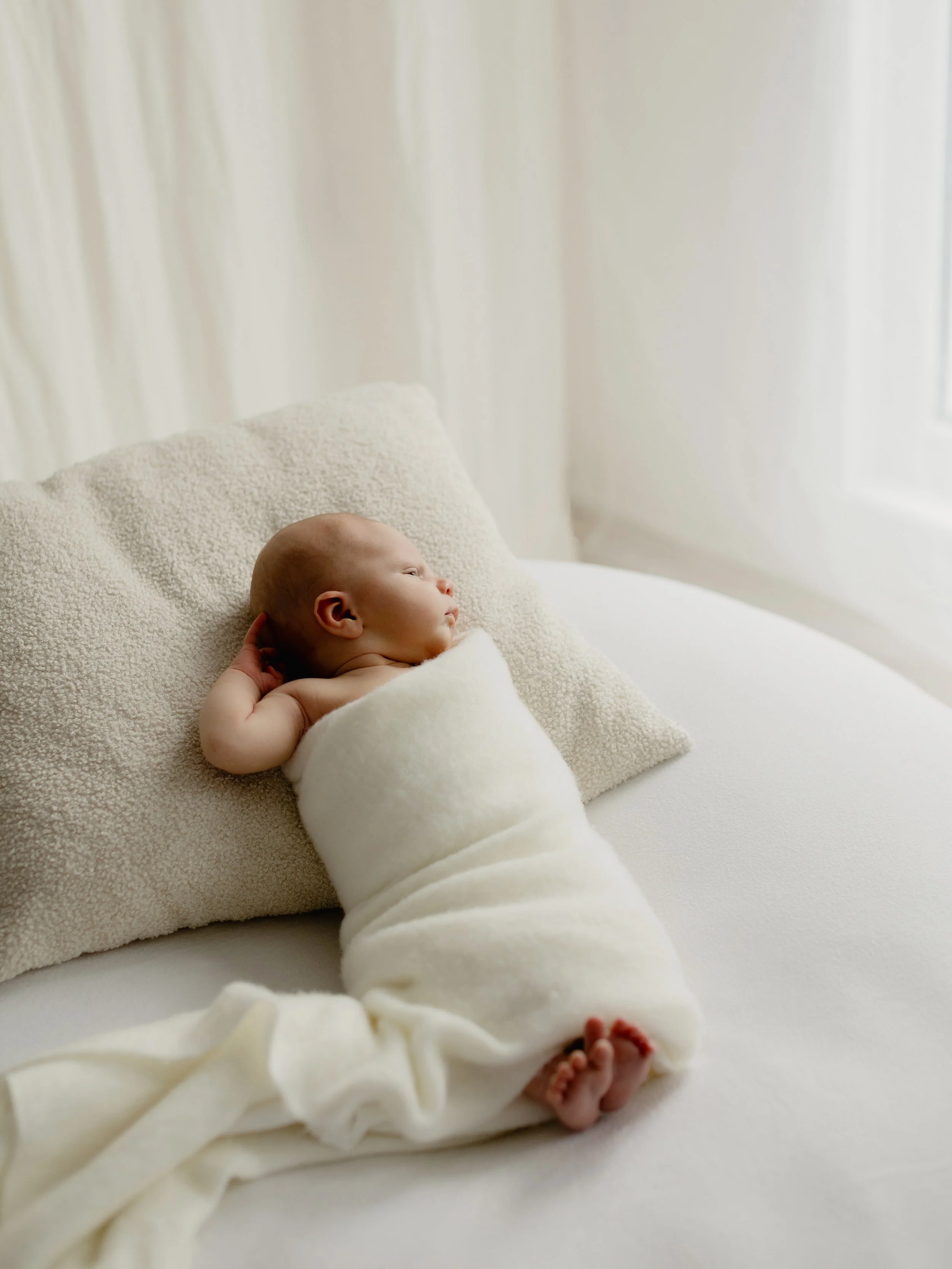 Newborn baby wrapped in cream during a natural newborn photography session in South Ockendon, Essex