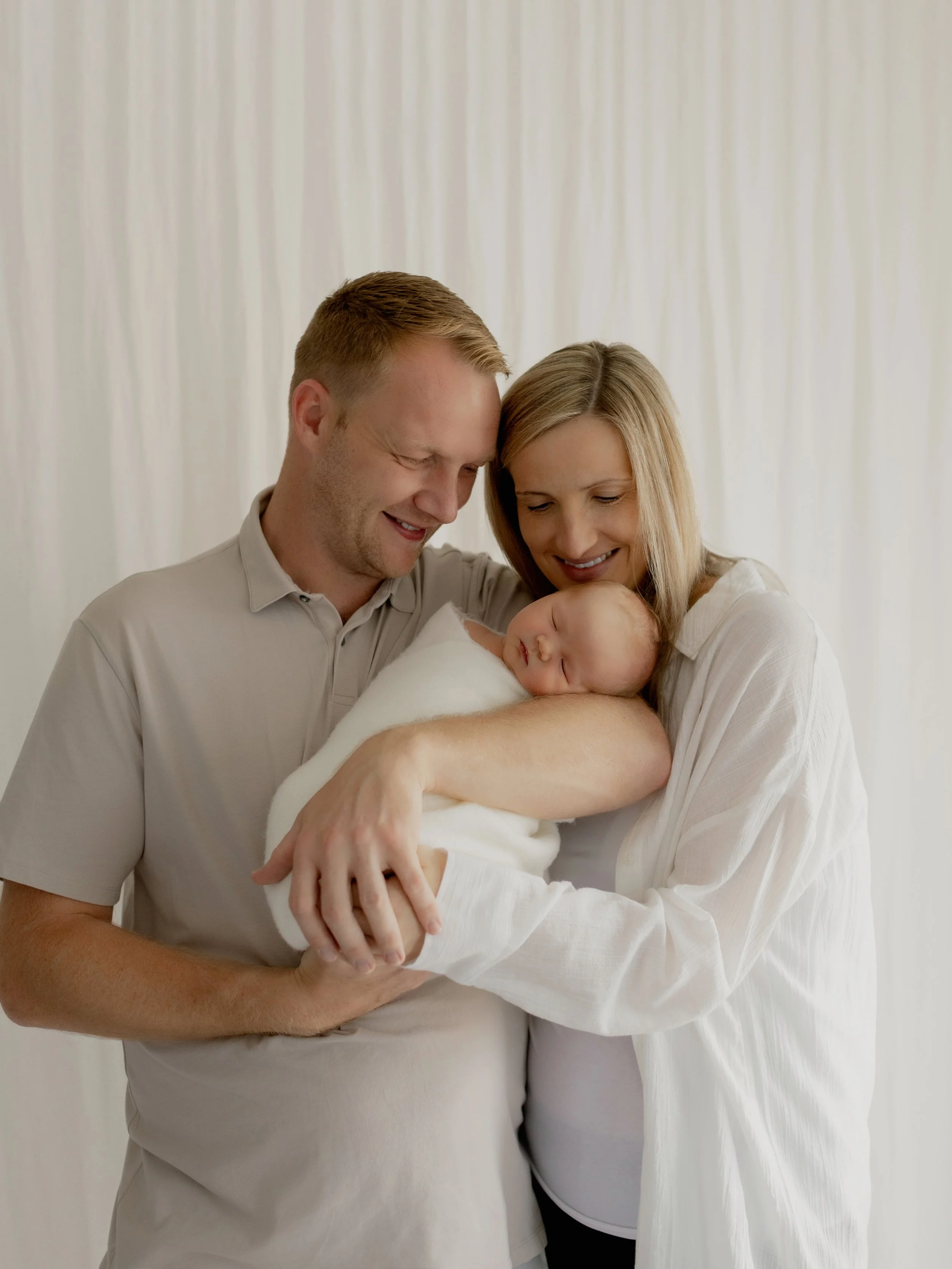 Mum and dad cuddling their newborn baby during a studio photography session