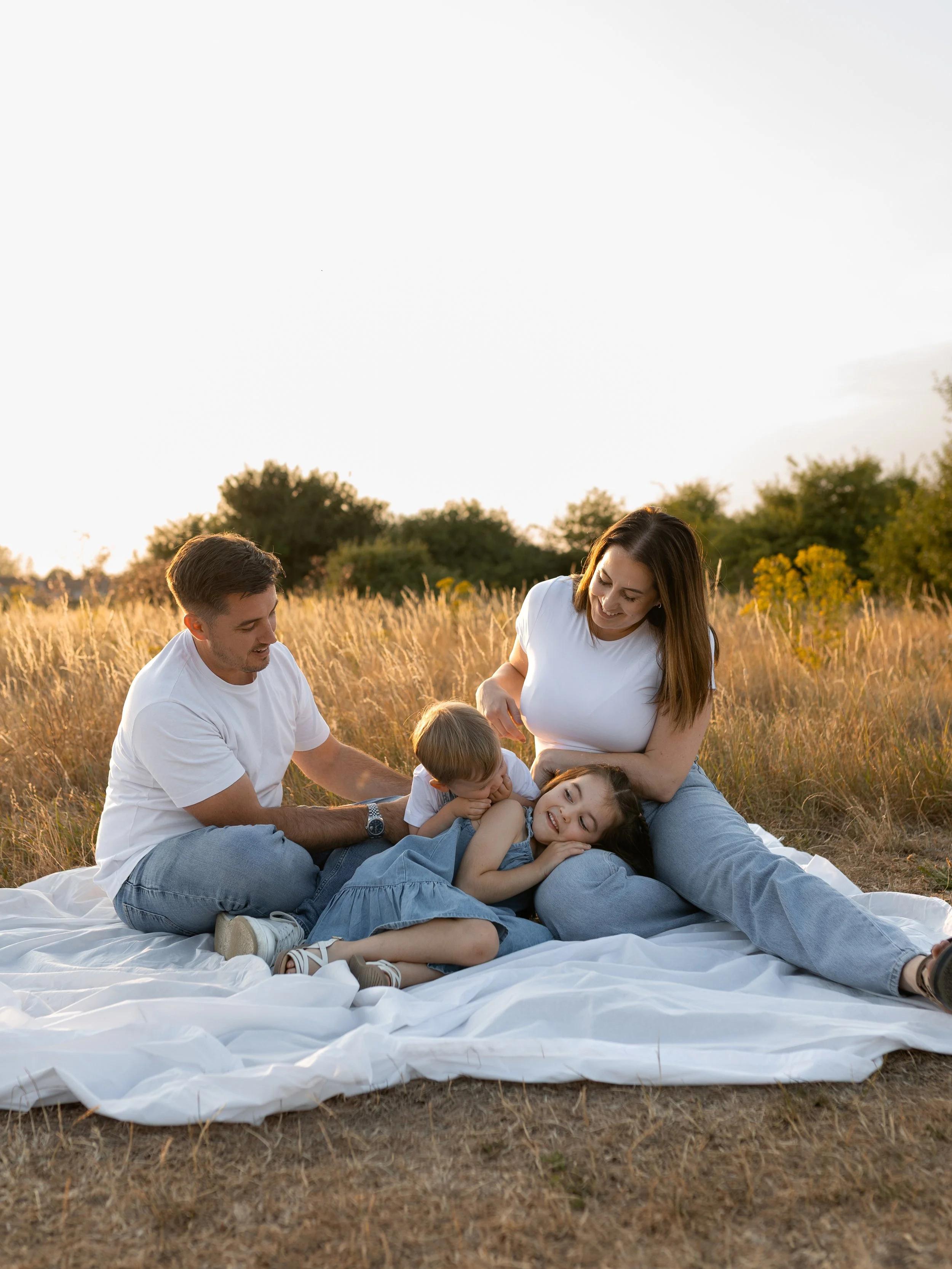 Family of four sitting together in a field during a relaxed outdoor family photography session in Essex.