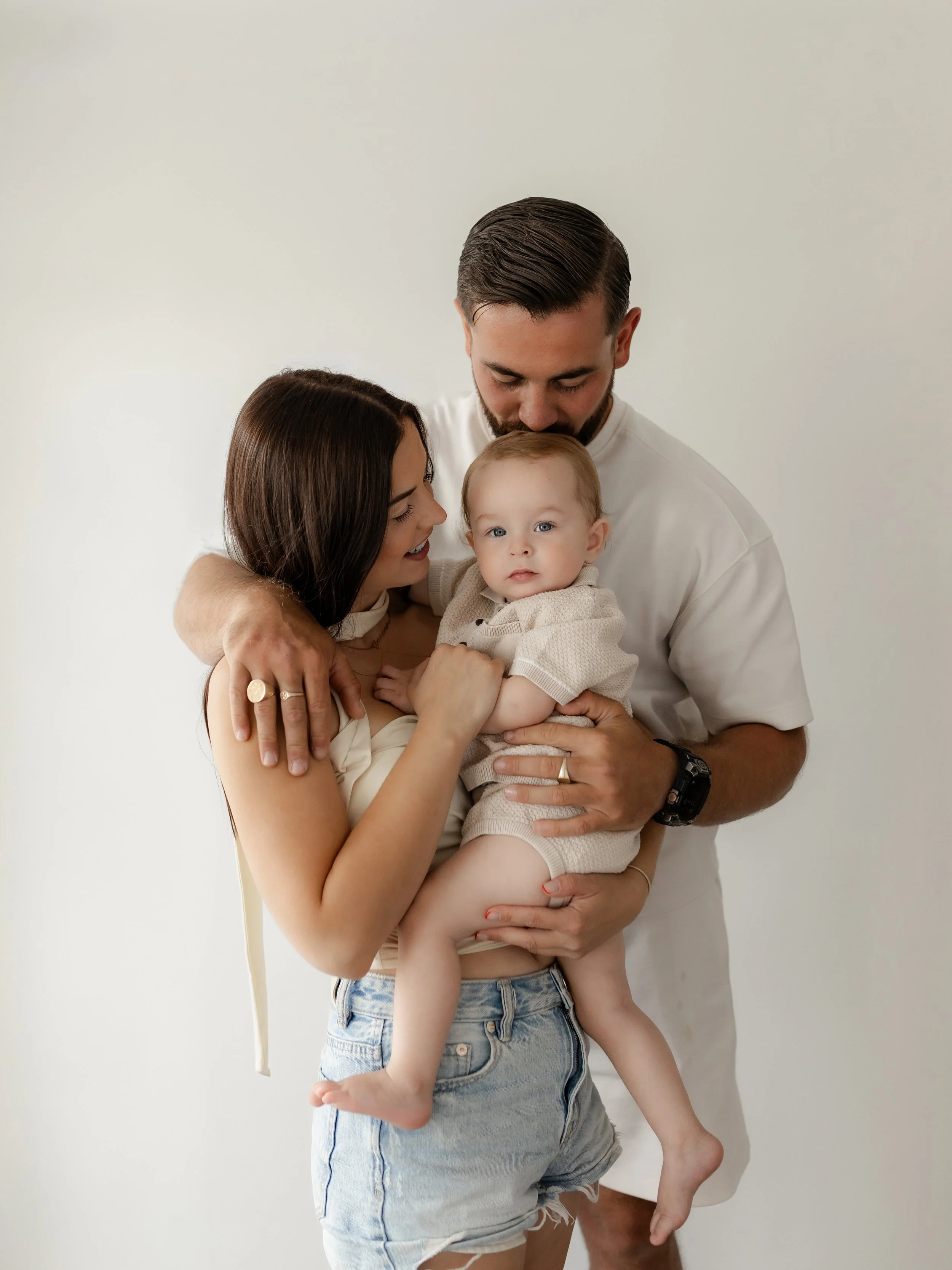 Mum and dad cuddling their baby during a relaxed milestone photography session at the studio.