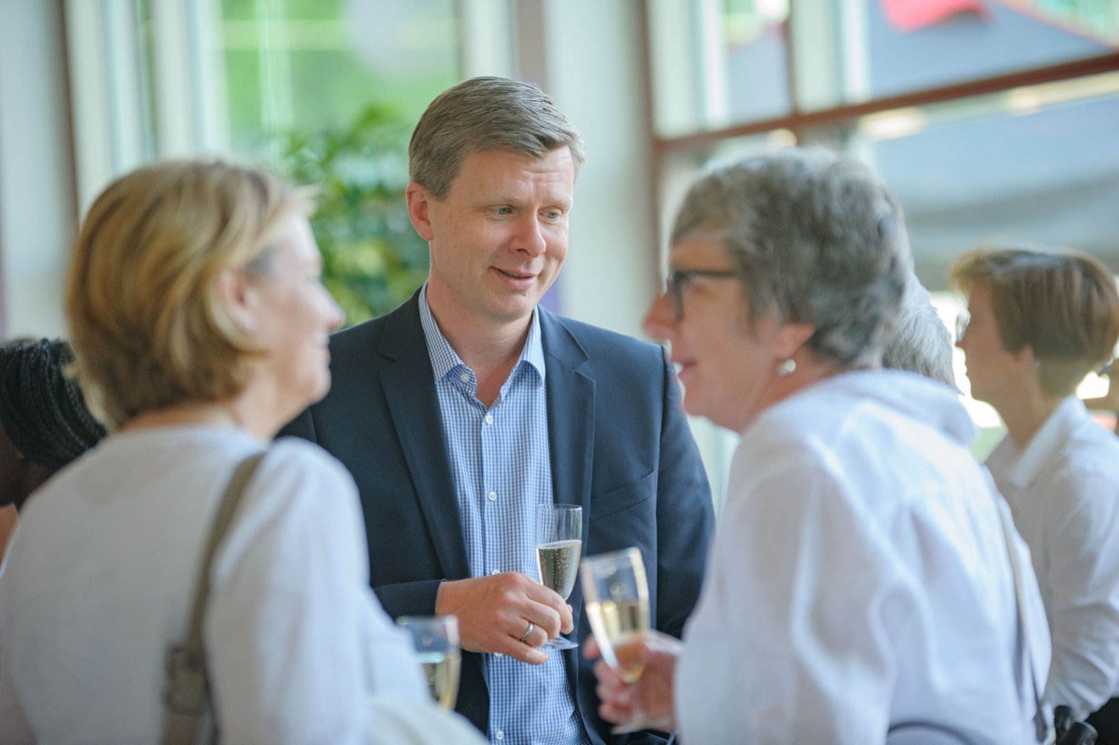 Menschen beim Empfang eines gesellschaftlichen Anlasses, trinken Sekt und unterhalten sich.
