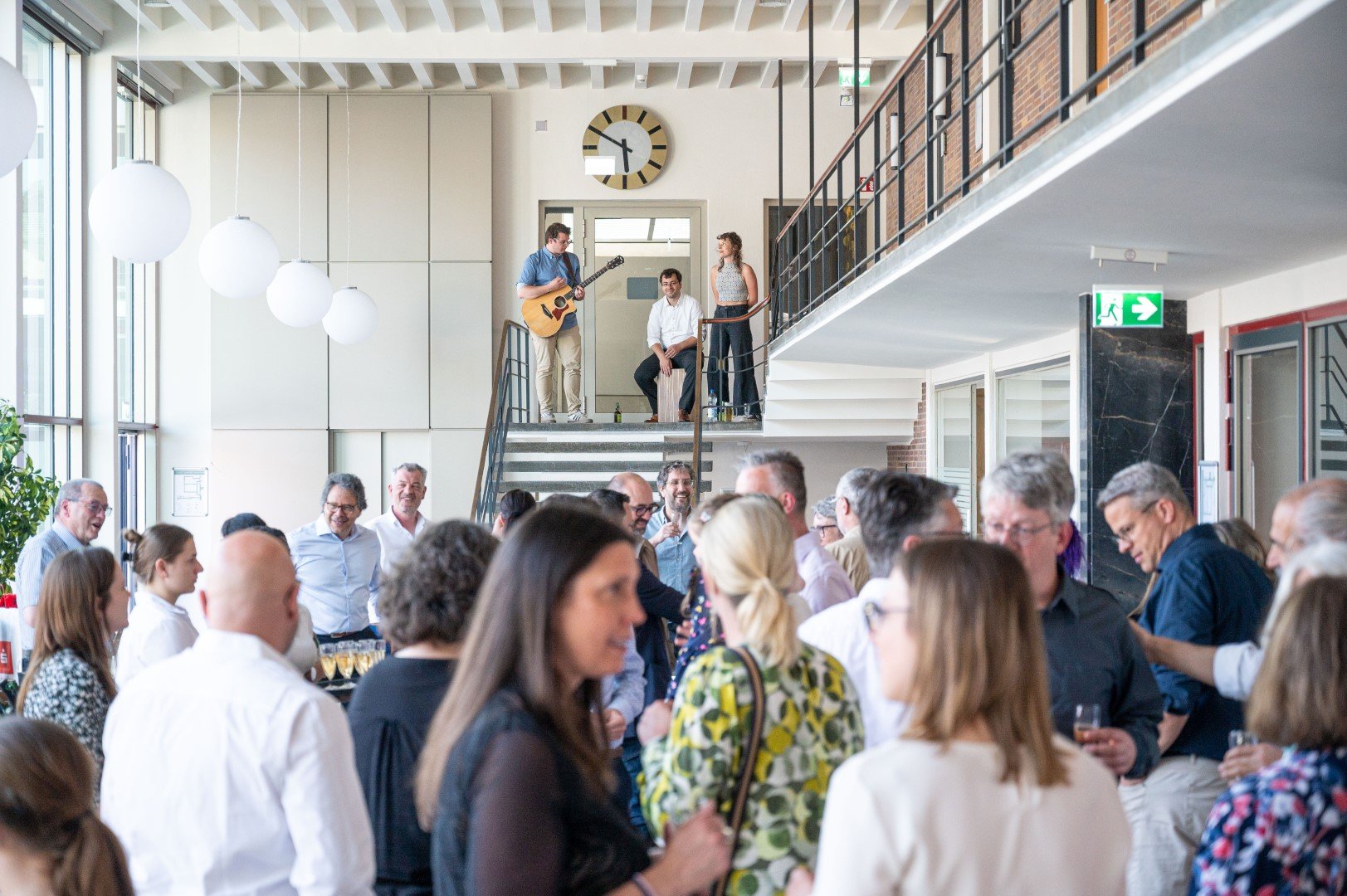 Menschen feiern und genießen sich in einer modernen, hellen Lobby mit Musik und Gesprächen.
