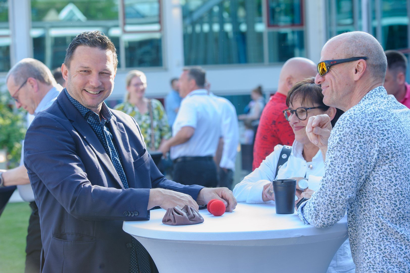 Menschen beim Networking bei einer outdoor Veranstaltung, lachen und sprechen an einem hohen Tisch