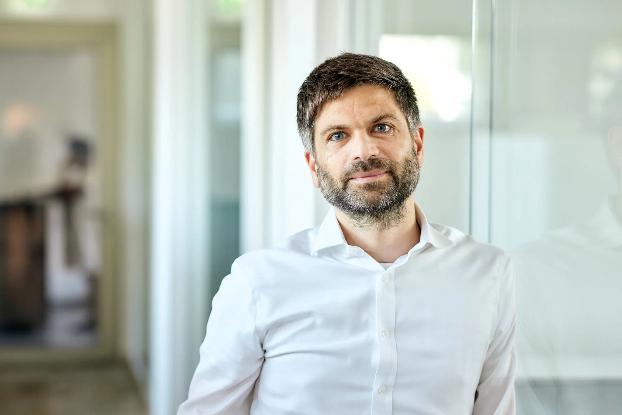 Karsten Mühlsteph von VSZ Rechtsanwälte, steht vor einem hell erleuchteten Hintergrund, vermutlich im Büro oder in einer modernen Innenraumumgebung.