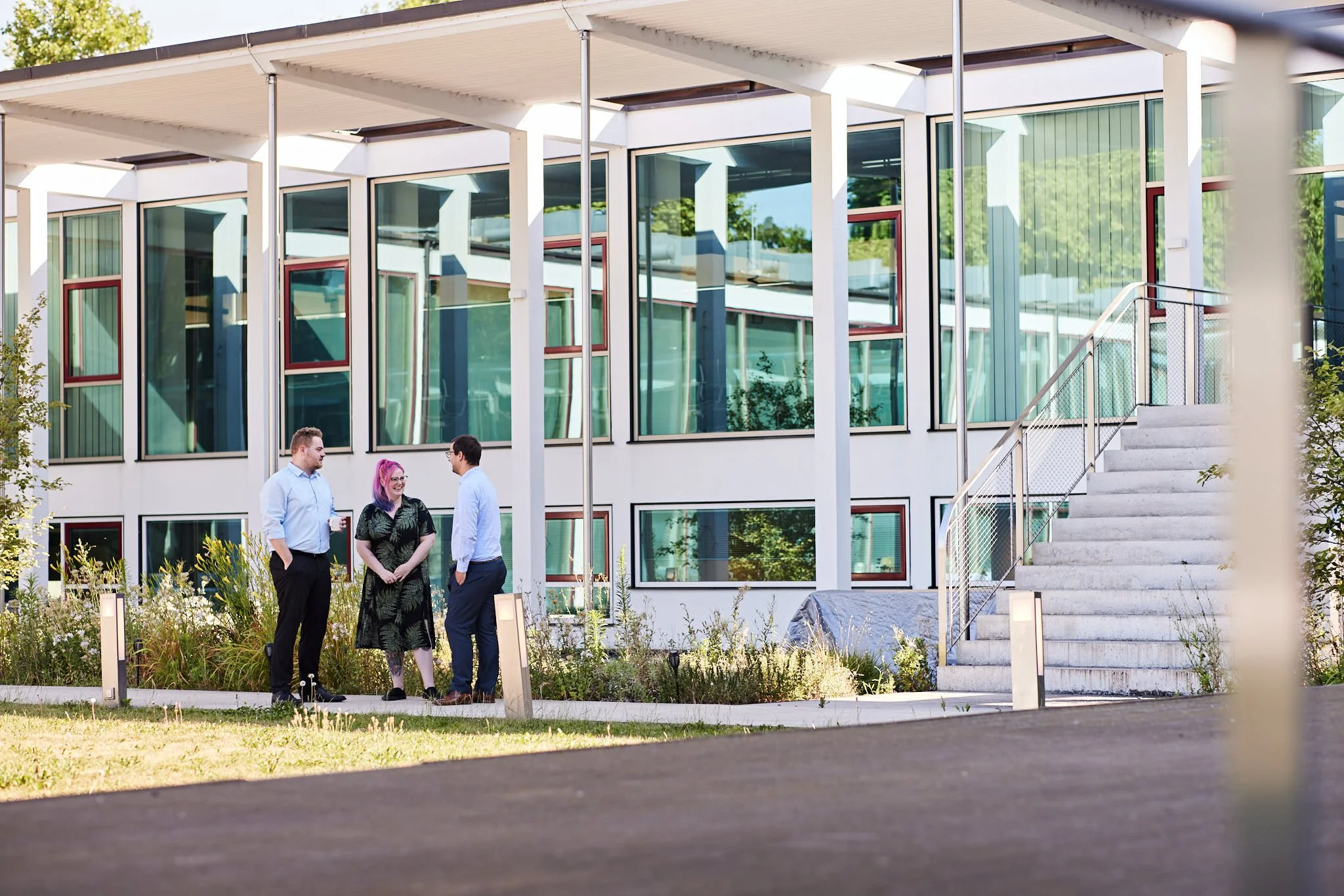 VSZ Rechtsanwälte im Gespräch vor einem modernen Gebäude mit großen Fenstern und weißen Balkonen.