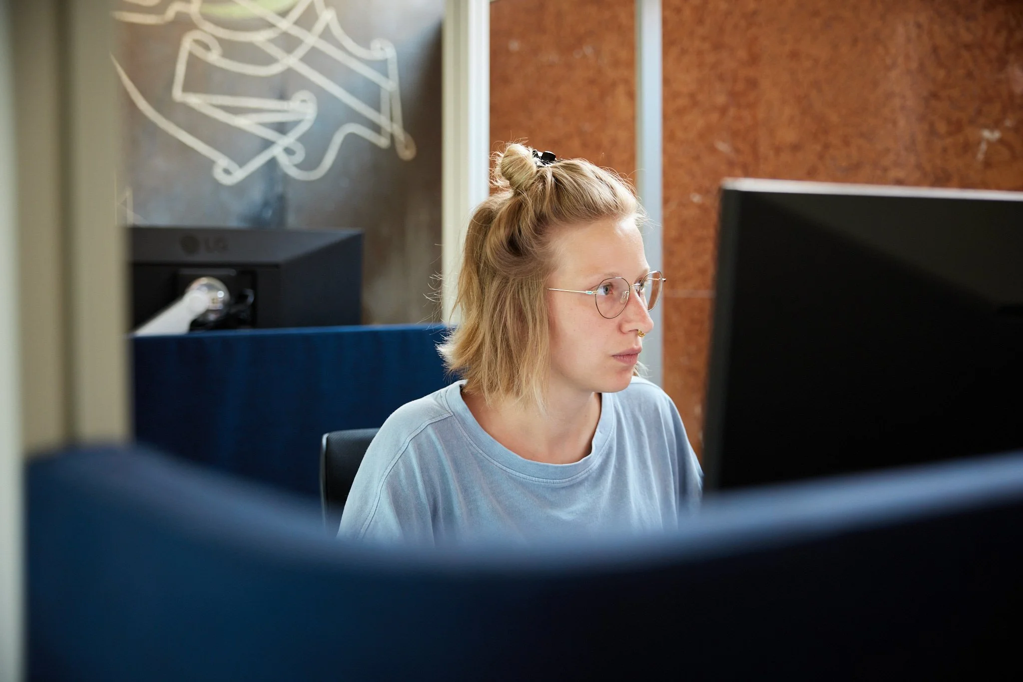 ReFa von VSZ Rechtsanwälte, arbeitet an einem Computer in einem Büro, im Hintergrund eine braune Wand.