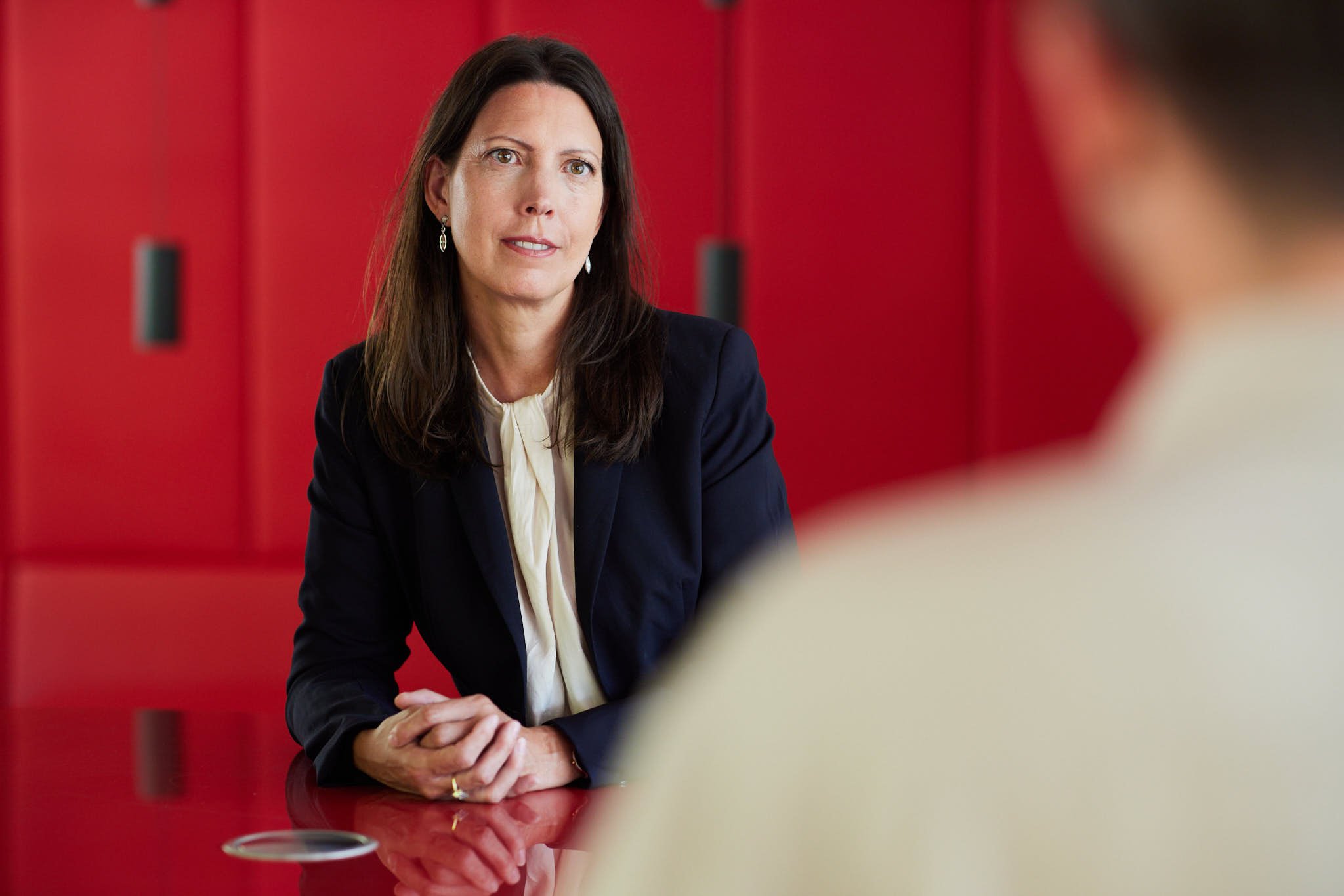 RAin Silke Ahlborn von VSZ Rechtsanwälte sitzt an einem roten Tisch in einem Gespräch mit einer anderen Person, die nur teilweise sichtbar ist.