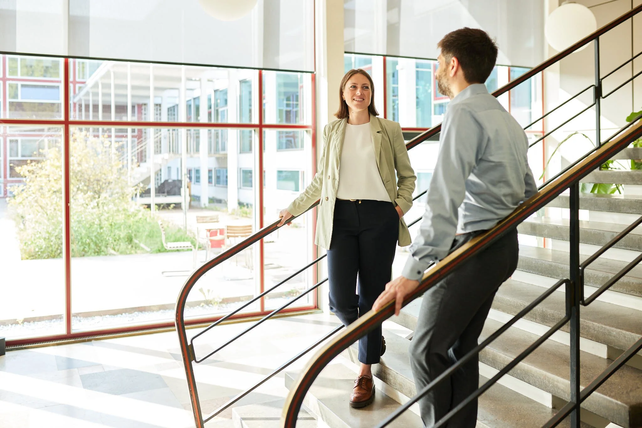 VSZ Rechtsanwälte unterhalten sich an einer Treppe in einem modernen Gebäude mit großen Fenstern.