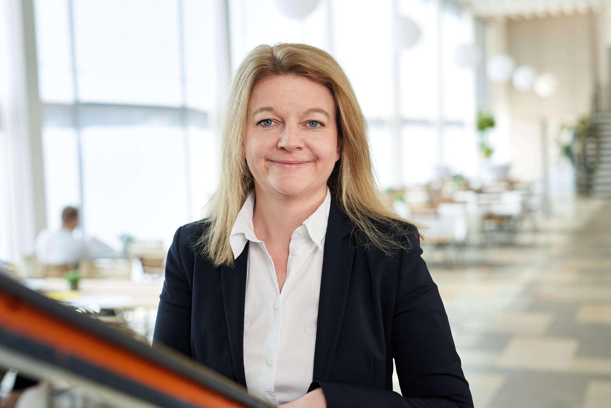 RAin Angela König von VSZ Rechtsanwälte trägt einen schwarzen Blazer und weiße Bluse in einem modernen Büro.