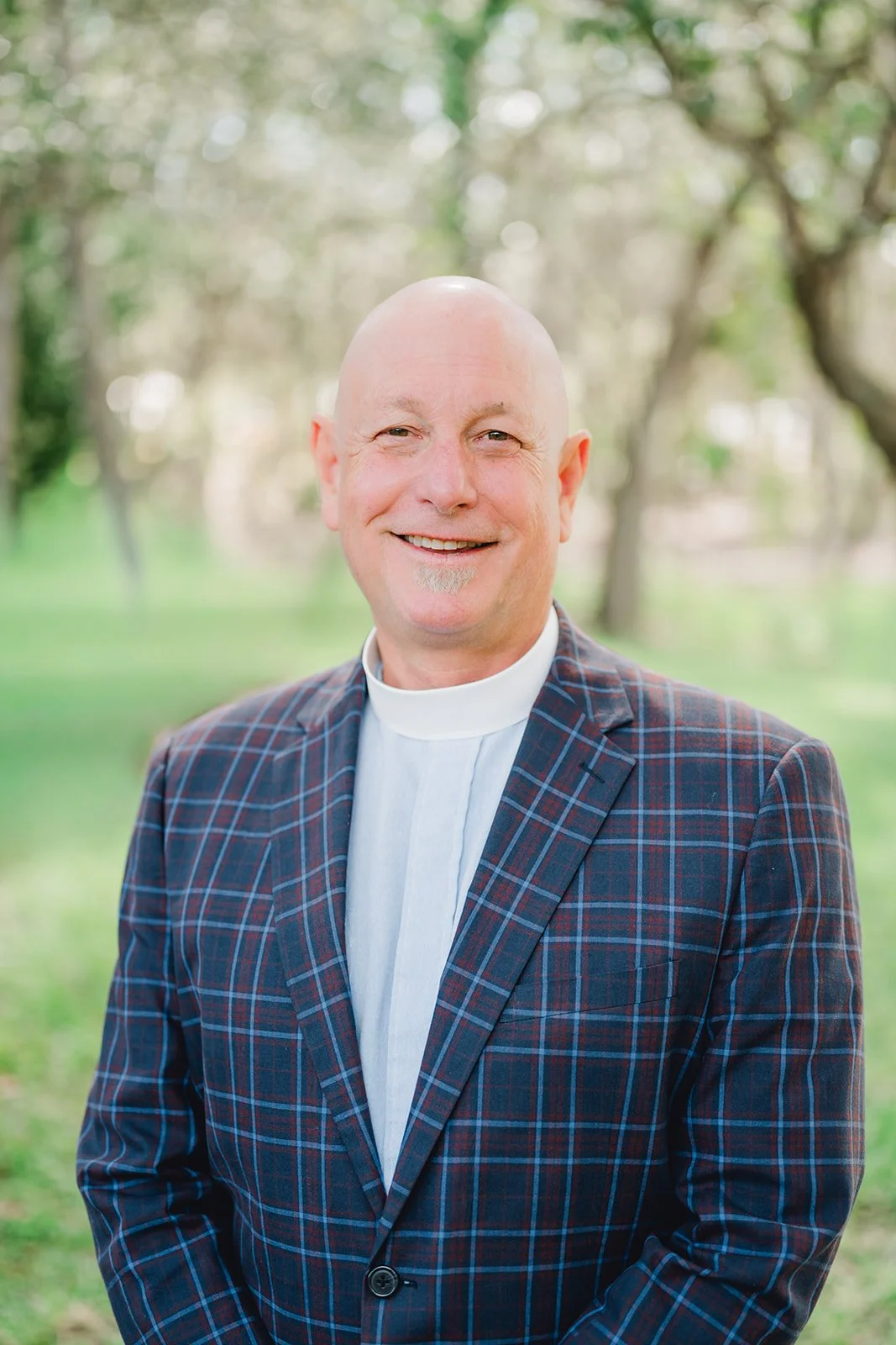 A smiling priest in white robes and vestments in worship service