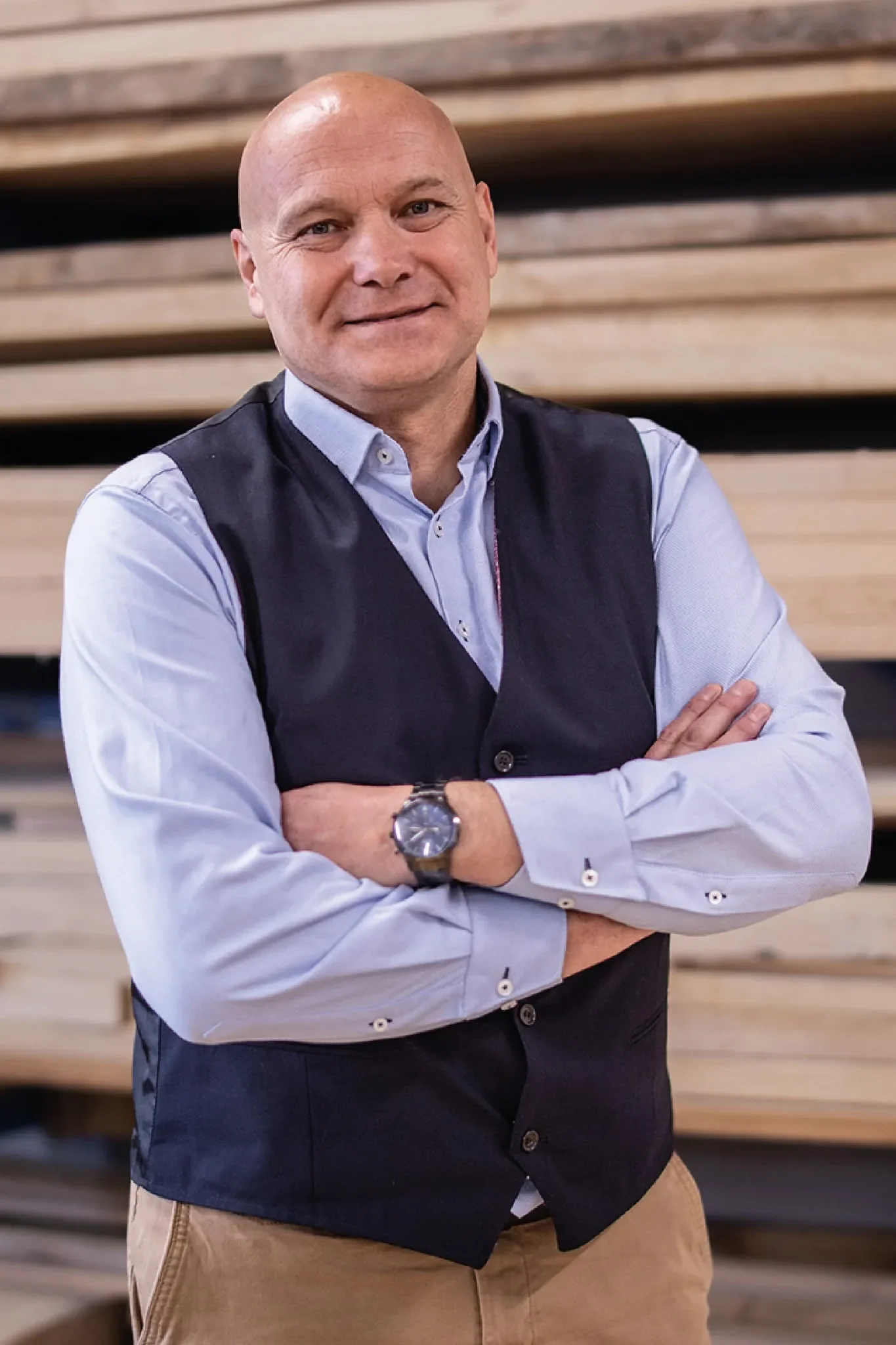 Halb-Körper-Portrait von Markus im Holzquadrat T-Shirt vor aufeinander gestapelten Brettern