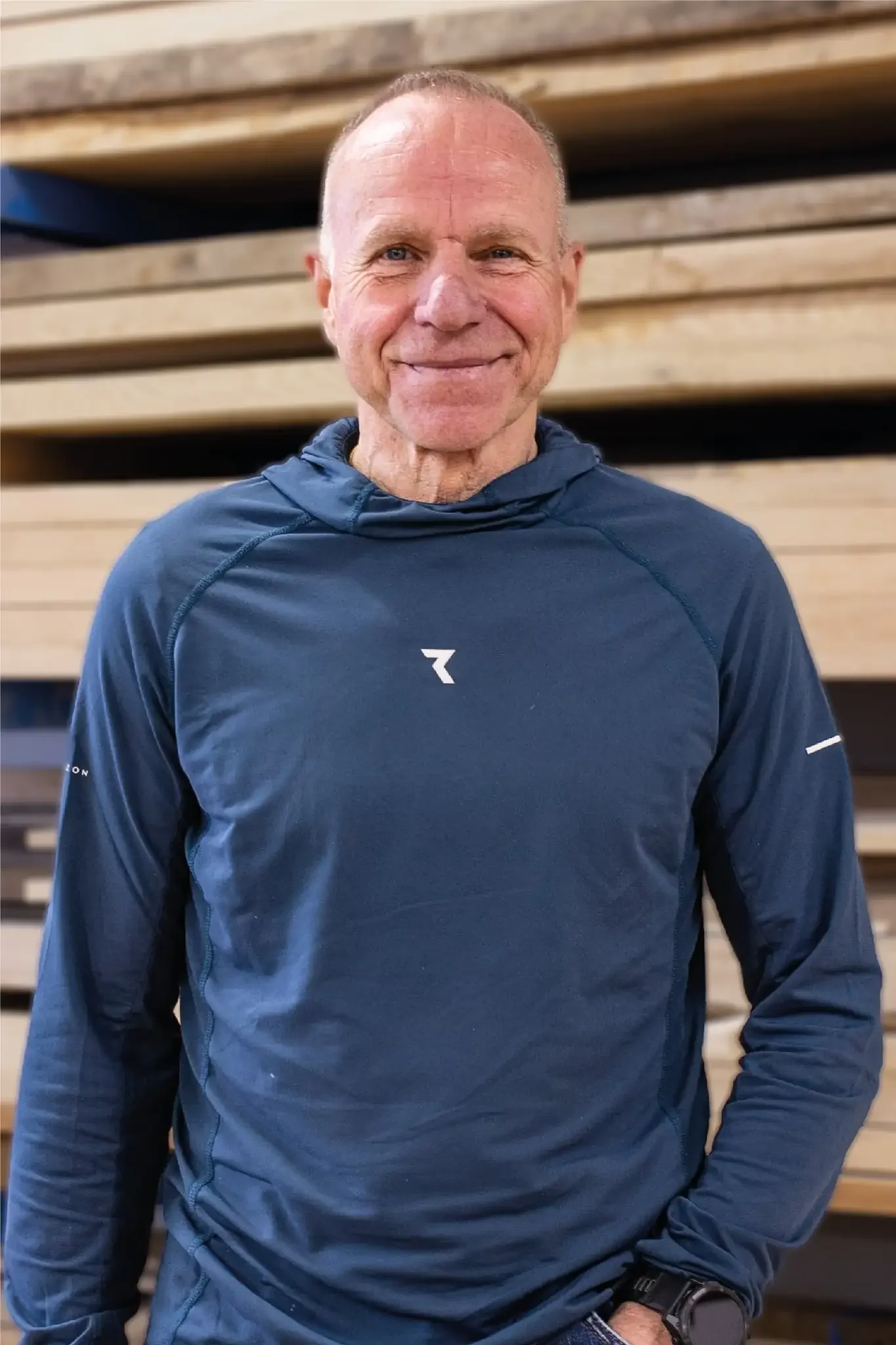 Halb-Körper-Portrait von Wolfgang im Holzquadrat T-Shirt vor aufeinander gestapelten Brettern