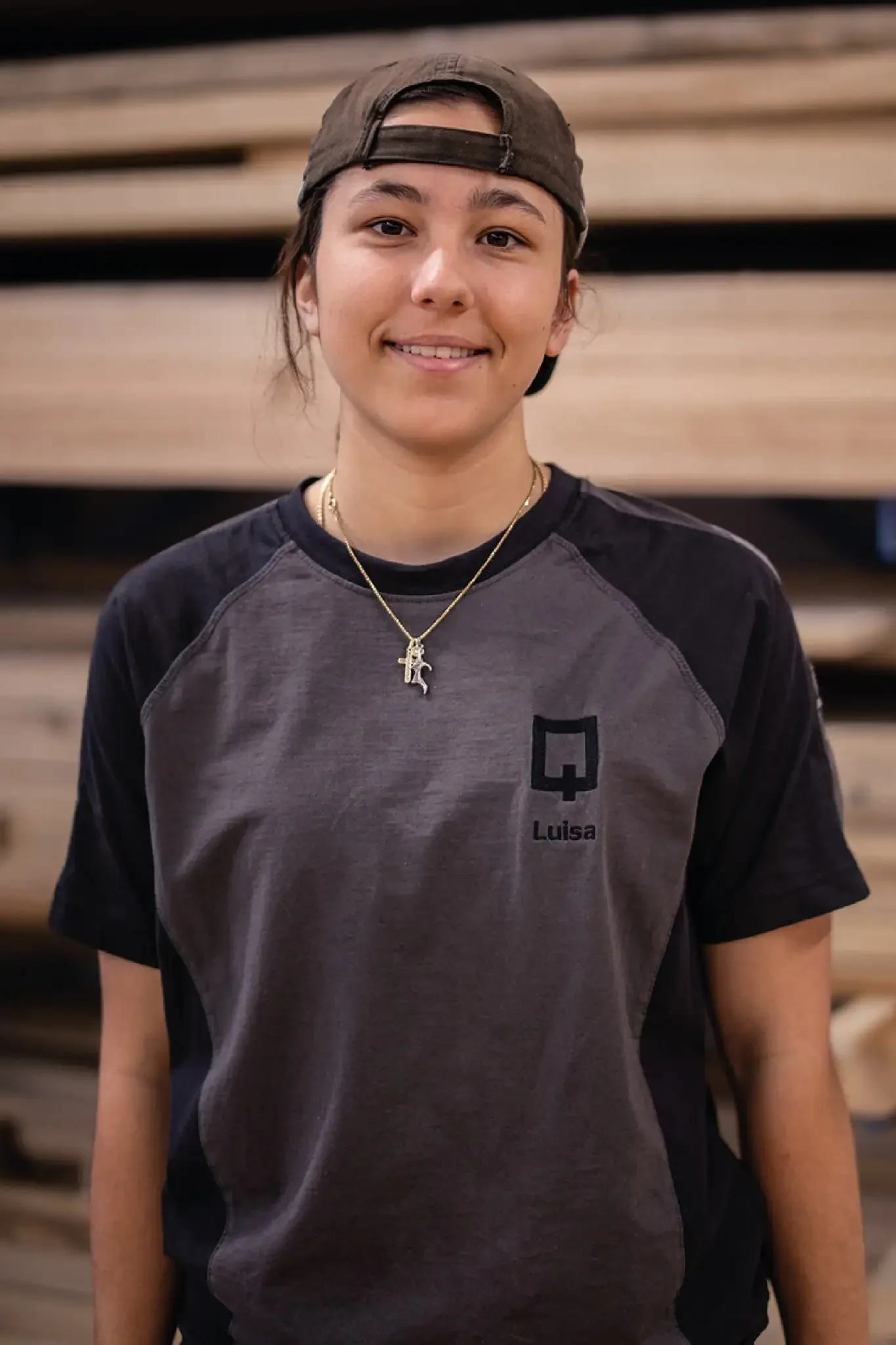 Halb-Körper-Portrait von Luisa im Holzquadrat T-Shirt vor aufeinander gestapelten Brettern