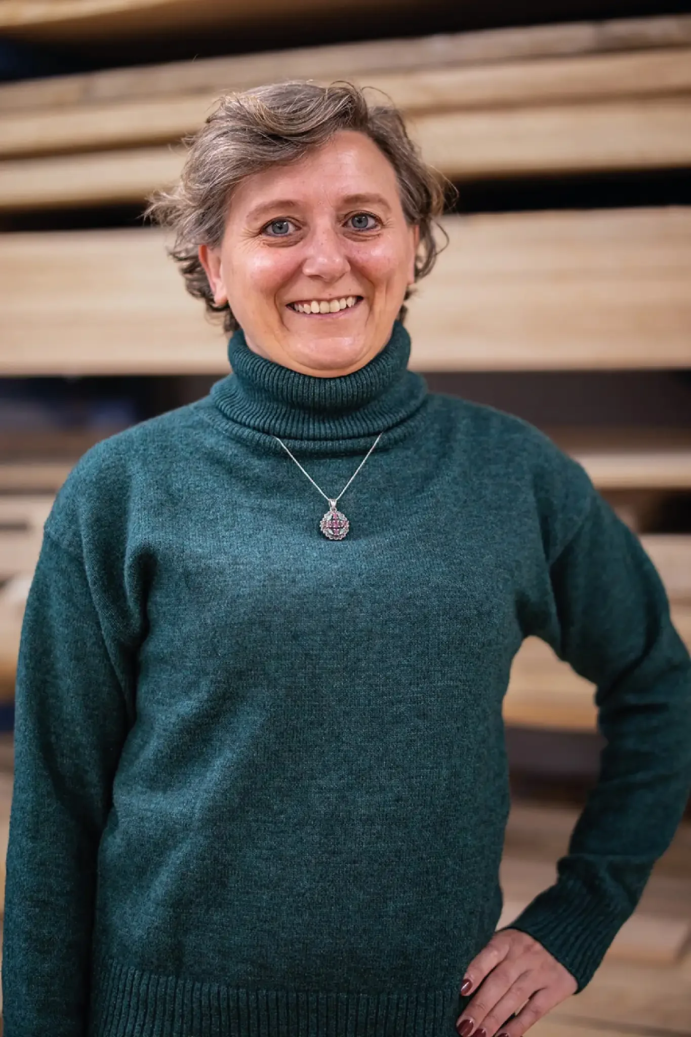 Halb-Körper-Portrait von Lucia im Holzquadrat T-Shirt vor aufeinander gestapelten Brettern