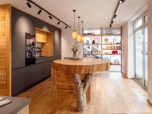 Modernes Küchenatelier mit Holztheke, Regal im Hintergrund und großen Fenstern.