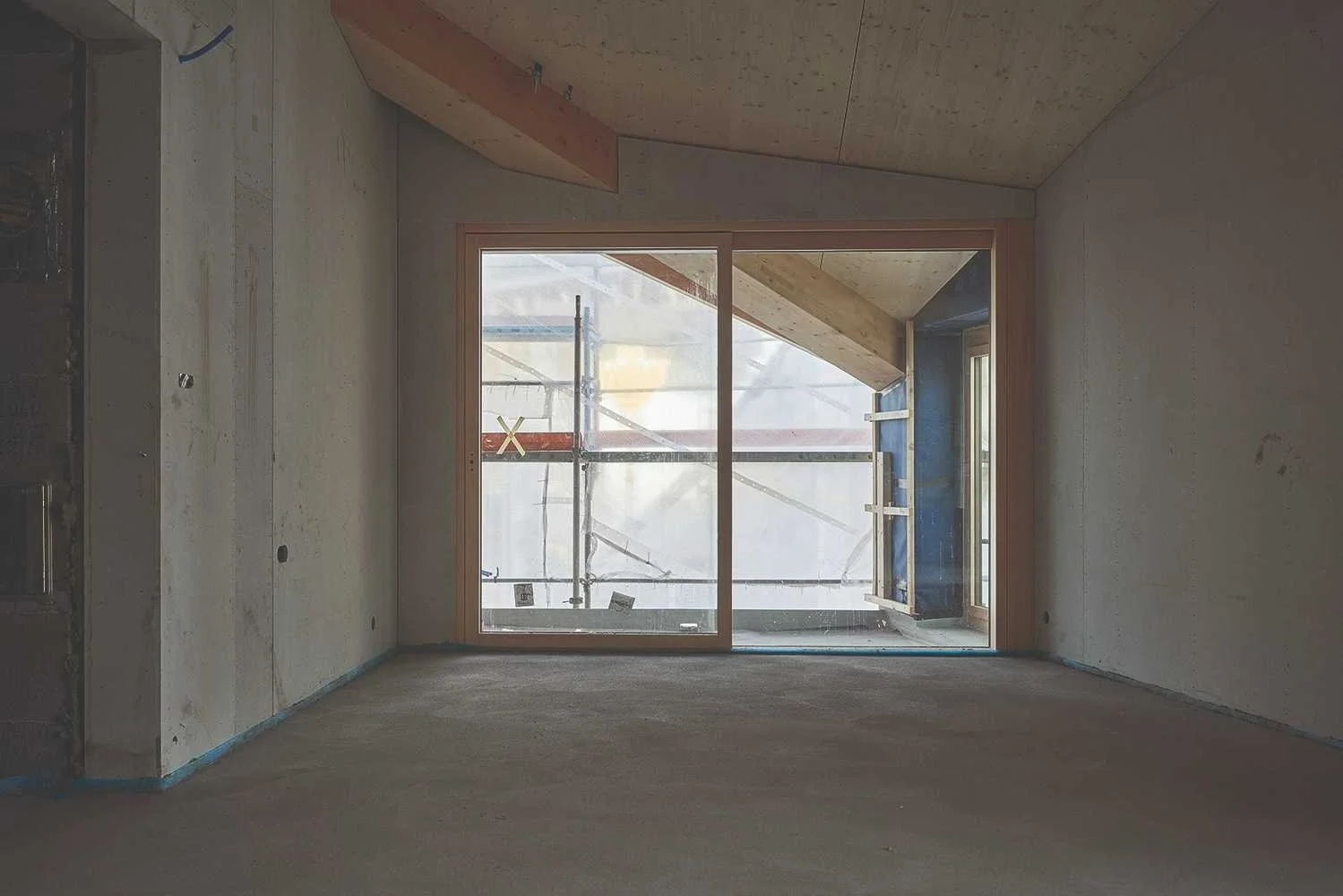 Rohbau eines Neubaus mit leerem Raum, großen Fensterflächen und sichtbarer Baustellensituation – Ausgangspunkt für die Planung einer neuen Küche.