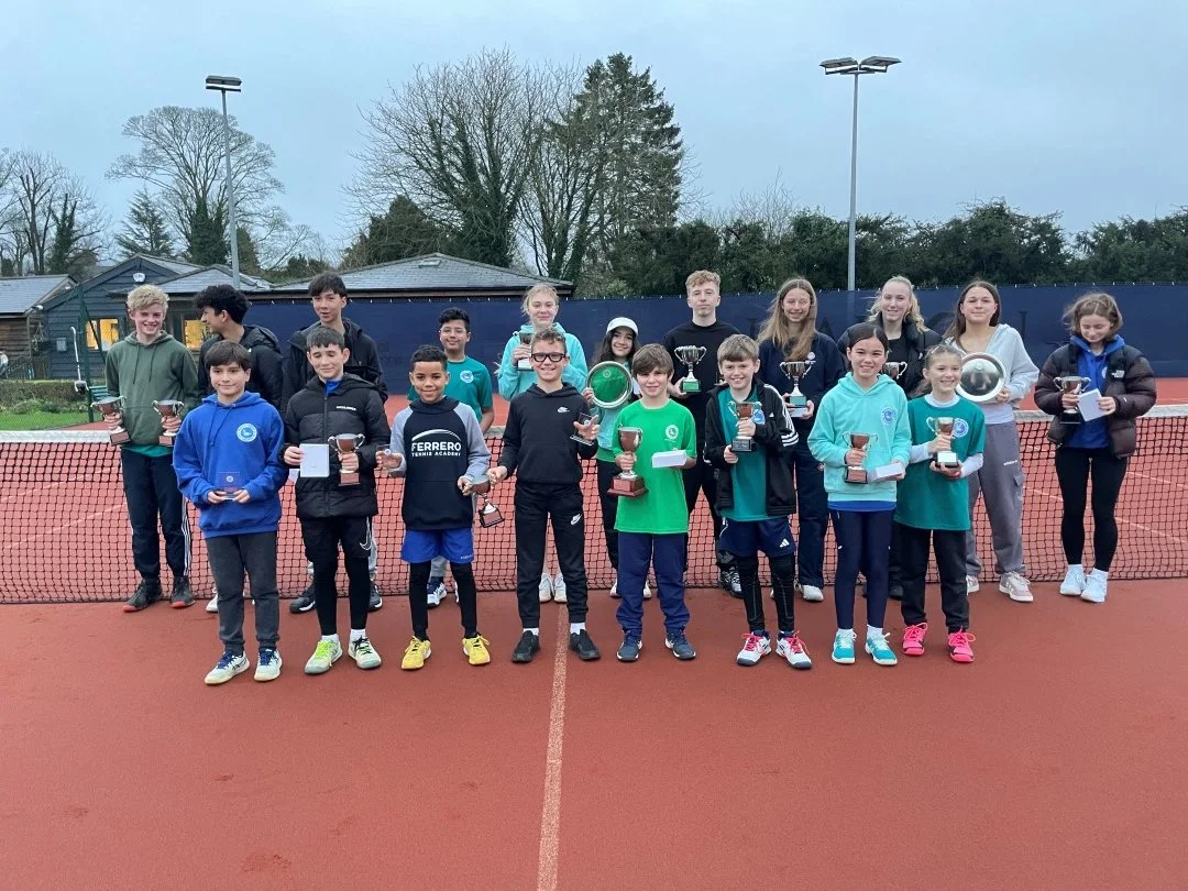 Bucks County Players standing on a tennis court holding trophies, celebrating a tennis award event.