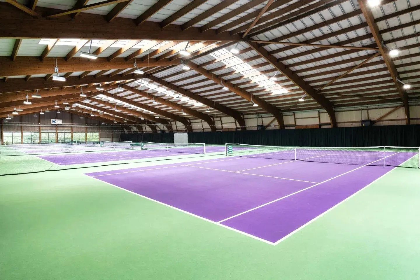 David Lloys Northwood Indoor tennis court with purple surface and green surroundings.