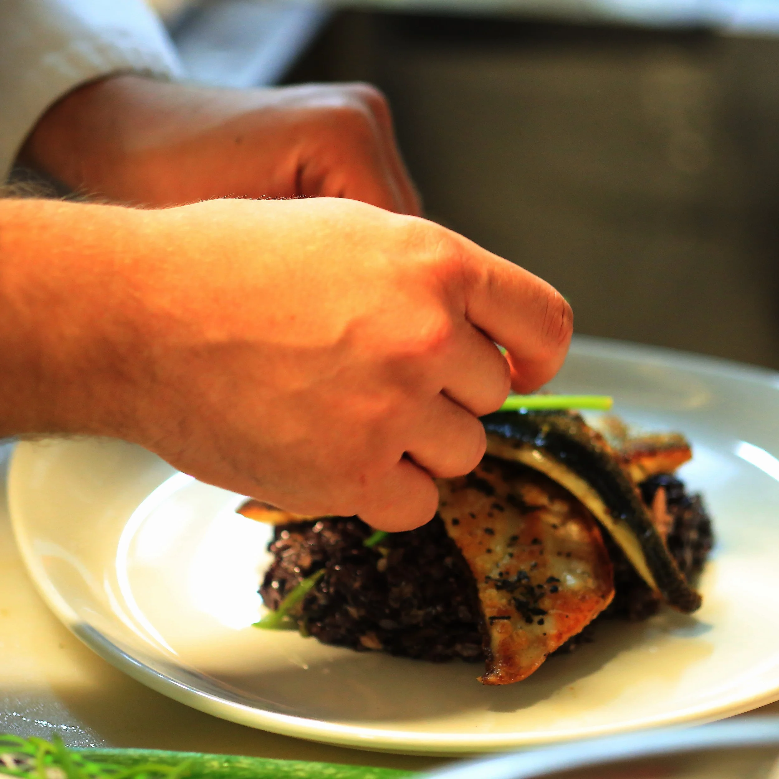 crafting Crispy pan-seared white fish fillets resting on a bed of black rice, finished with a sprig of fresh thyme.