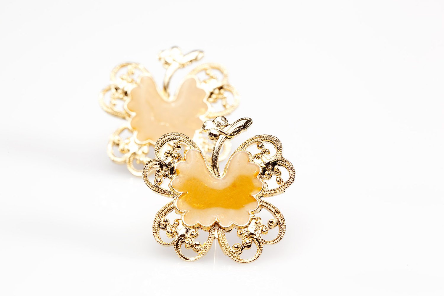 Gold butterfly-shaped earrings with intricate filigree details on a white background.