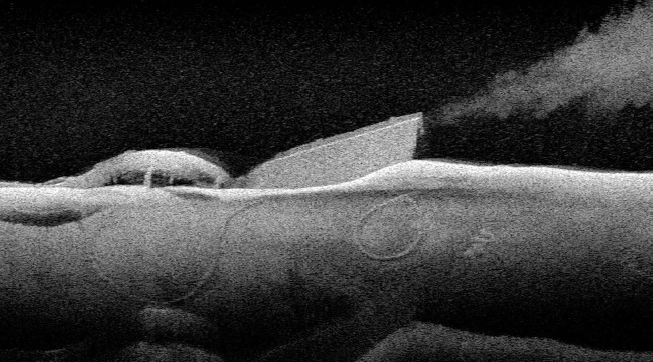 A helicopter flying over a desert landscape with sand dunes.