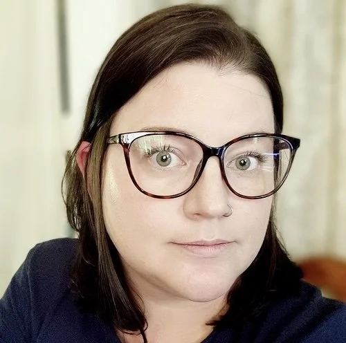 Portrait of a woman with dark brown hair, wearing glasses
