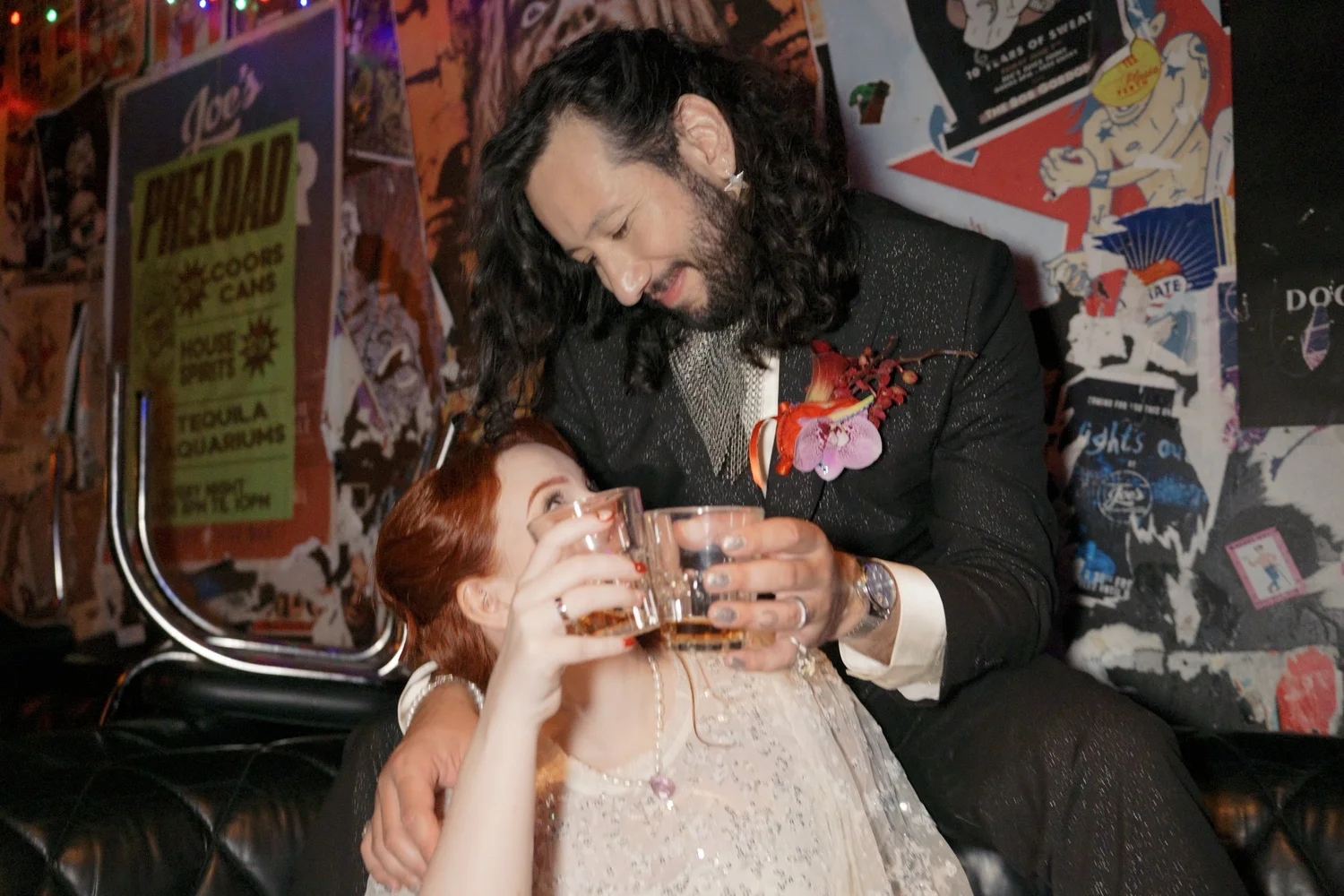 A bride and groom laughing together over drinks