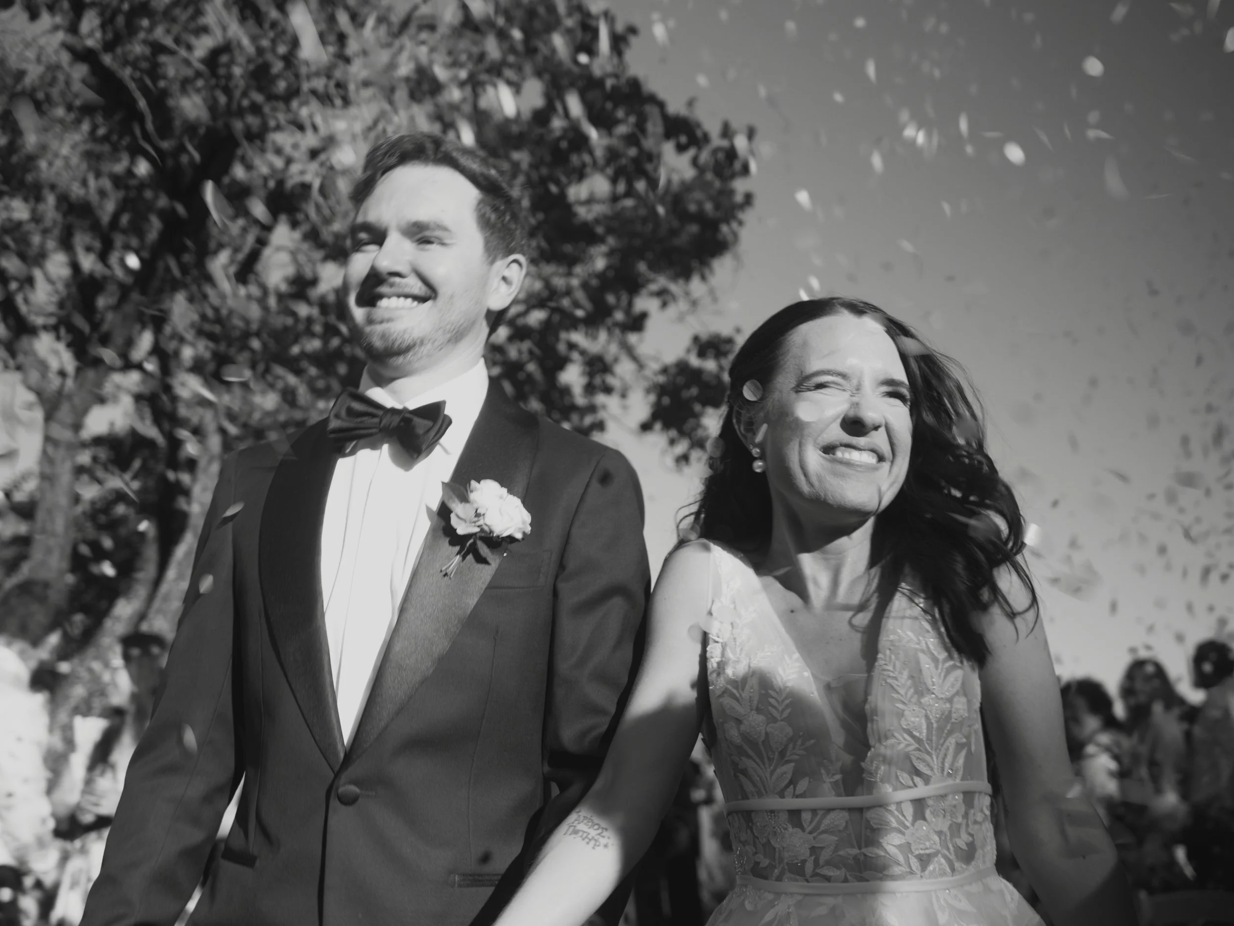 Christie and Robert laughing through confetti as they walk back down the aisle