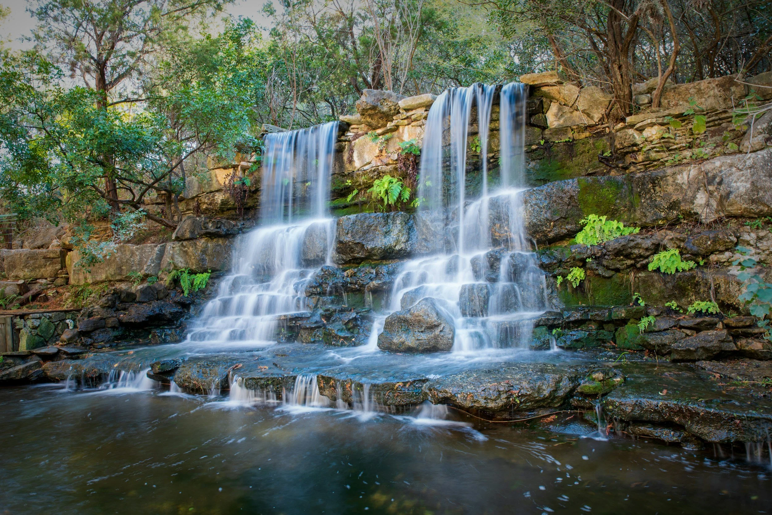 Waterfall cascading over rocks surrounded by trees and greenery