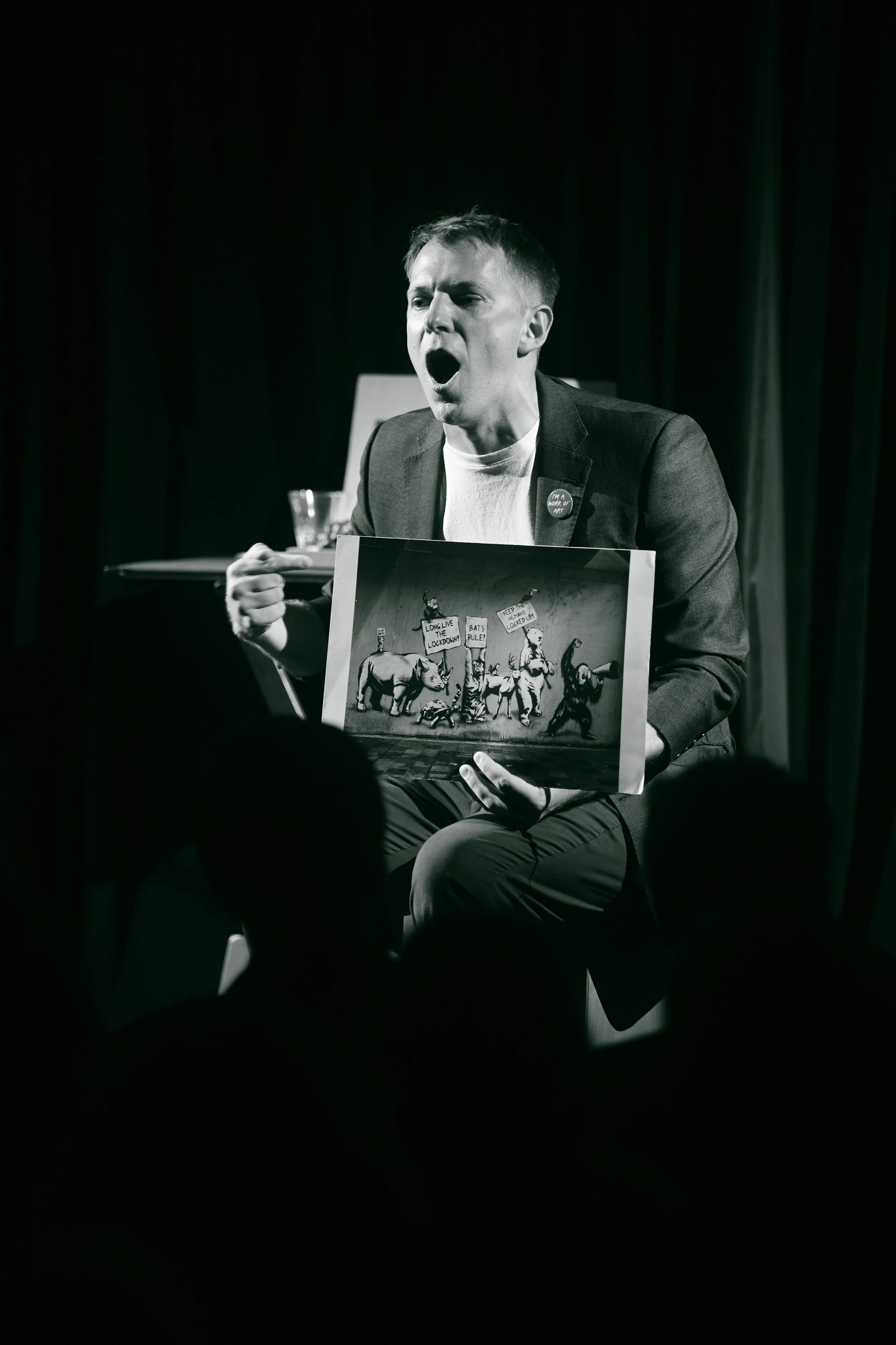 A person on stage holding a puppet show with animal puppets and mechanical props, performing for an audience.