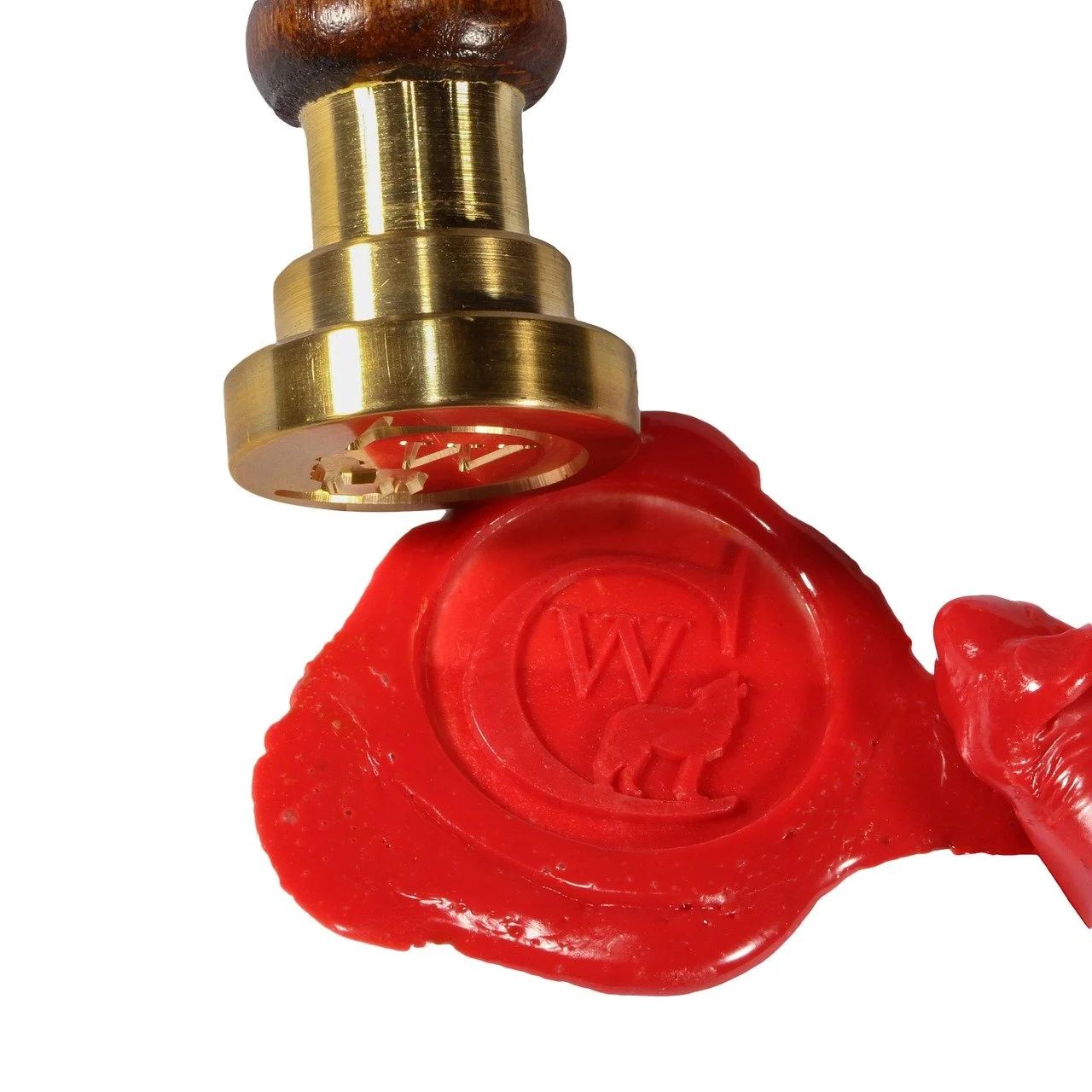 A brass wax stamp pressing a red wax seal with an embossed letter 'W' and a small animal figure, held by a hand.