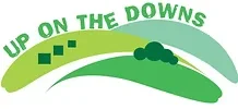 Logo with green curved text 'Up on the Downs' above a stylized landscape with rolling hills and a tree.