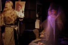 A woman with long blonde hair taking a selfie in a mirror, with blurred figures and a purple light in the background.
